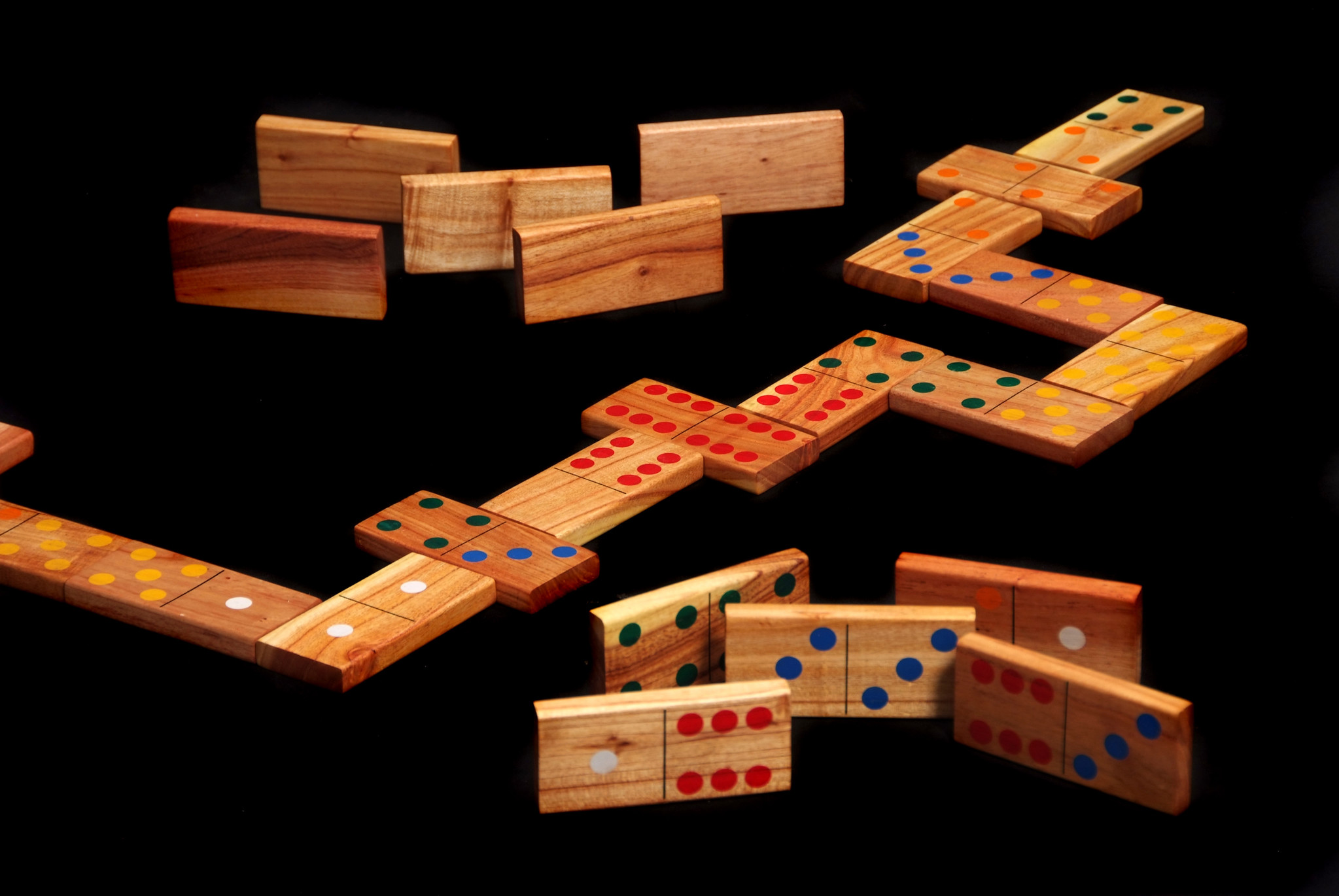 Holz-Domino auf schwarzer Oberfläche angeordnet, einige bilden ein Zickzackmuster.