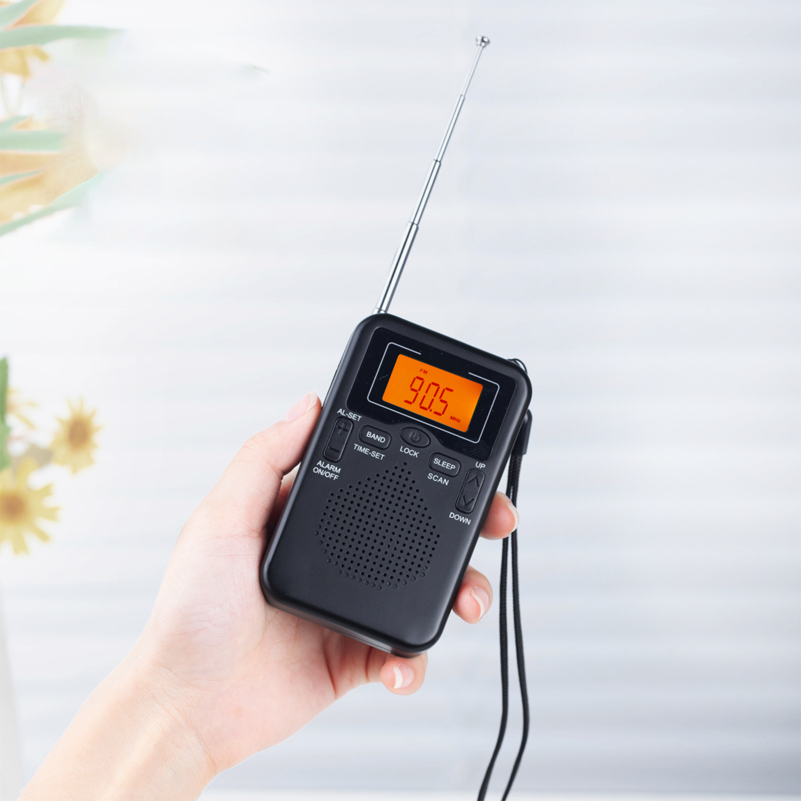 Hand hält schwarzes Radio mit 90,5 MHz, Antenne ausgezogen, auf weißem Hintergrund.