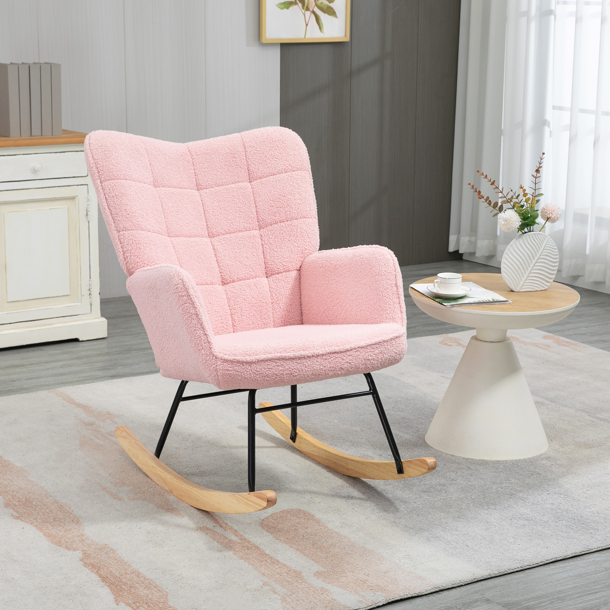 Ein rosa Teddybär-Schaukelstuhl mit schwarzem Gestell und Holzschaukeln, kleiner Tisch mit Dekoration.