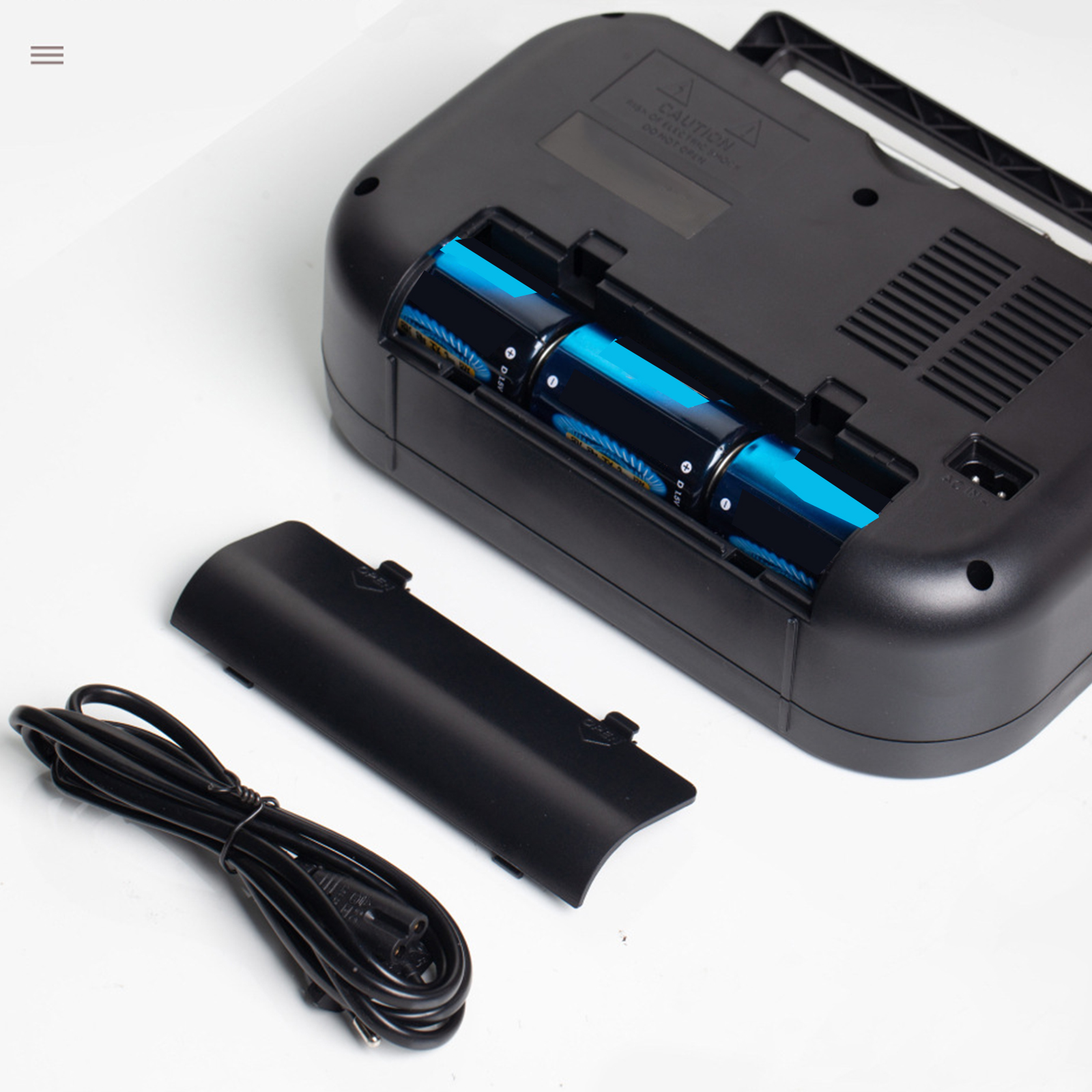 Schwarzes Gerät mit offenem Batteriefach, drei blauen Batterien und einem Netzkabel.