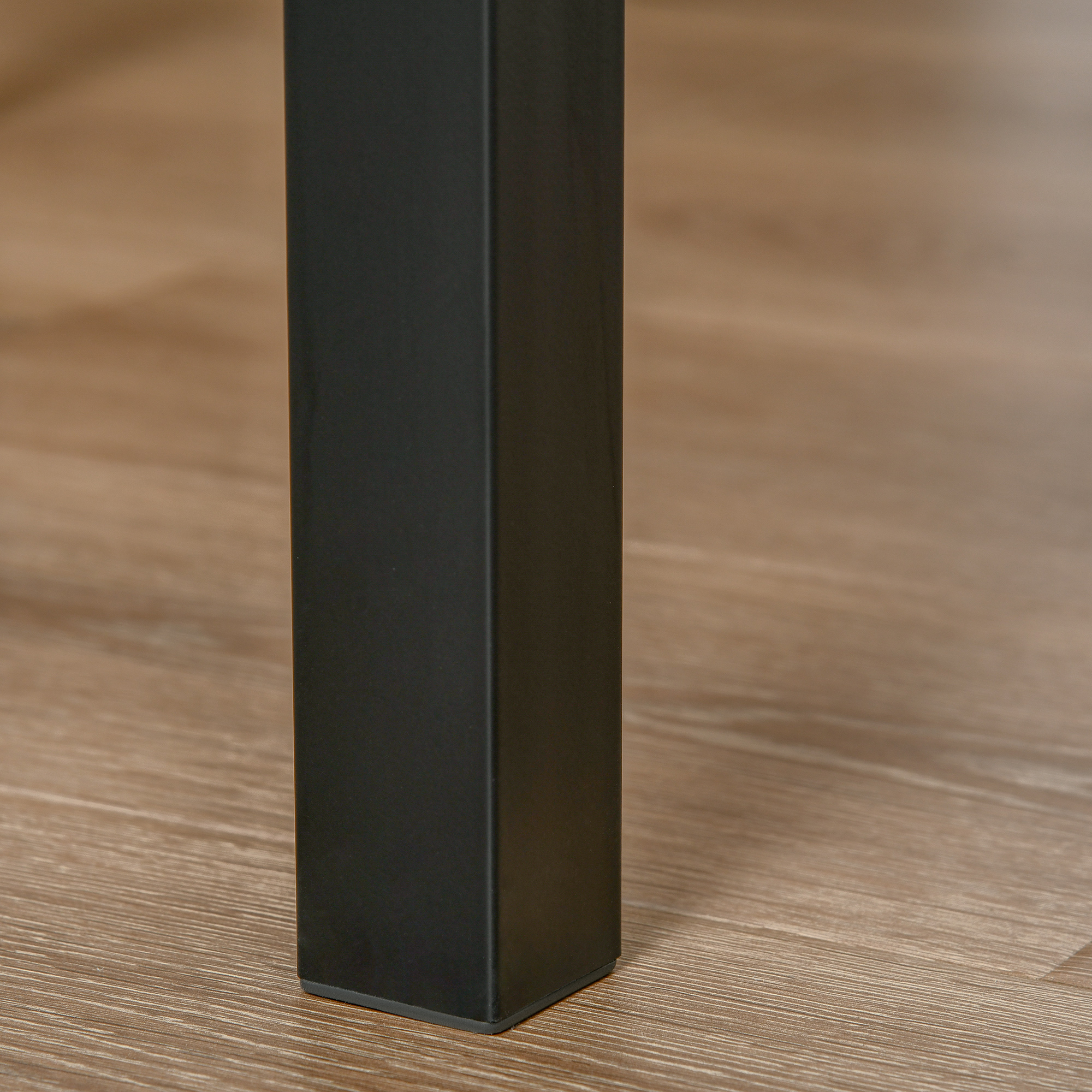 Schwarzes Tischbein mit quadratischer Form, auf einem Holzboden gezeigt, detaillierte Ansicht.