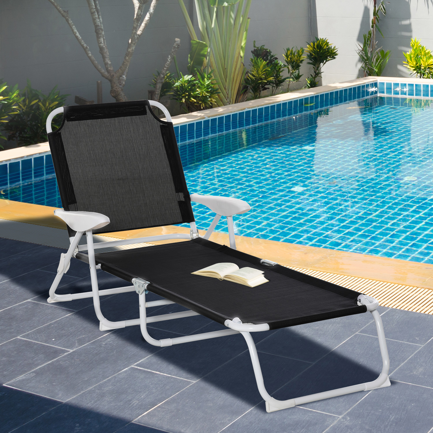 Strandstuhl am Pool. Stuhl ist offen. Buch auf dem Sitz. Pool und Bäume im Hintergrund.