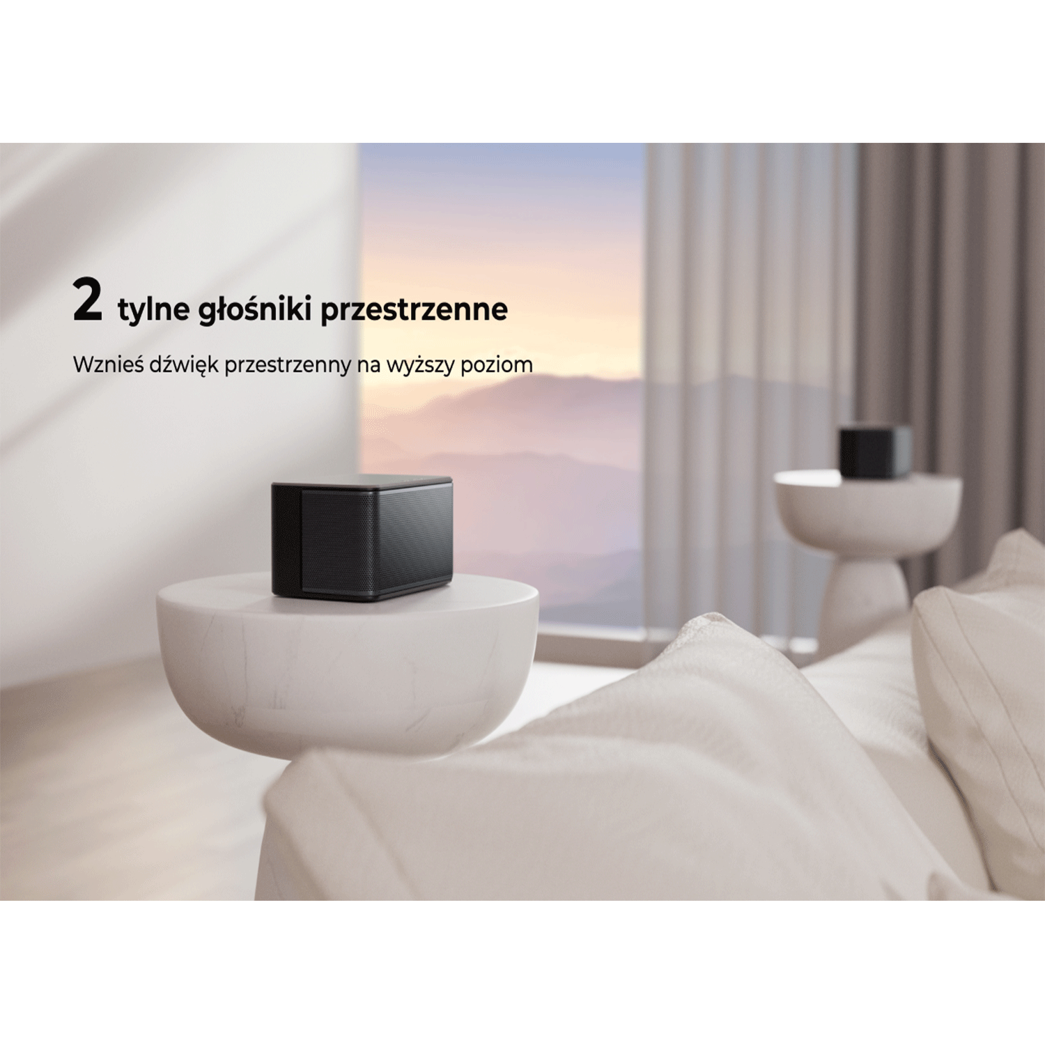 Czarny głośnik na białym, zakrzywionym stole. Biała sofa w tle z oknem i widokiem.