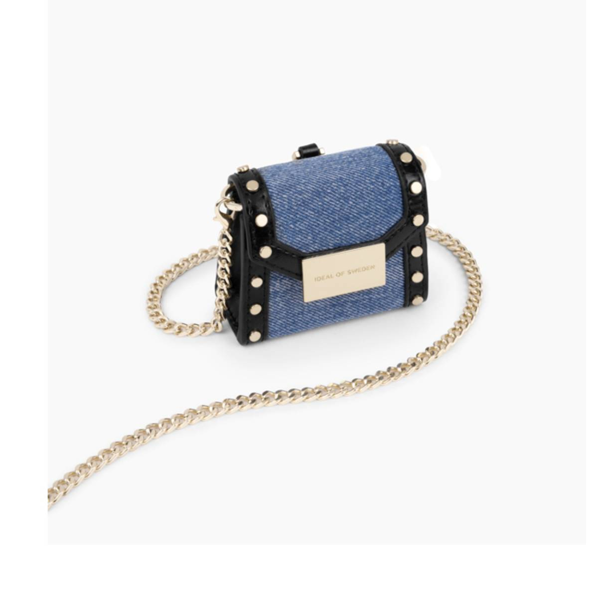 Un pequeño bolso de mezclilla con cadena dorada. El bolso está sobre un fondo blanco.