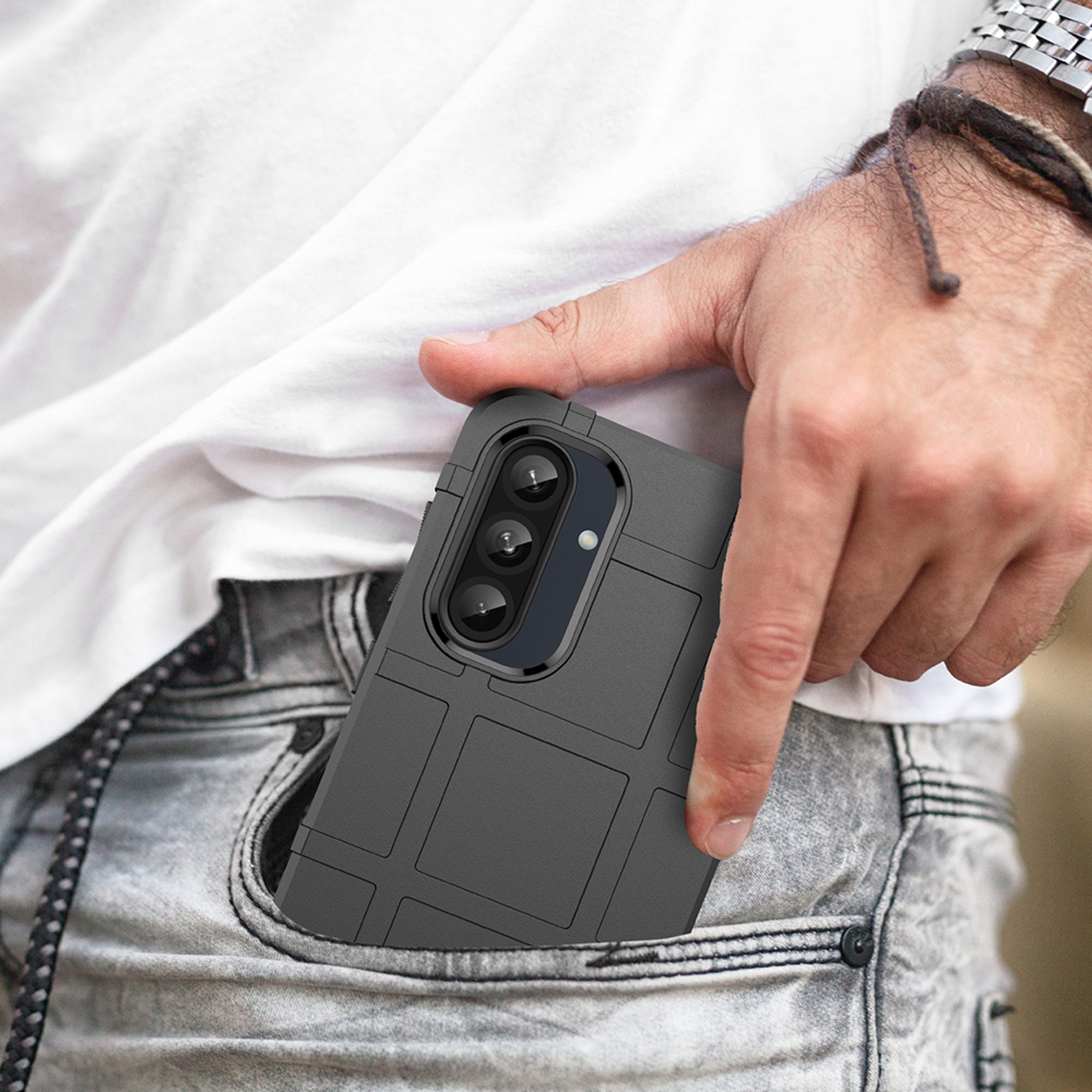 Een hand met een telefoon in een zak. De telefoon heeft een zwarte hoes met een rastertextuur.