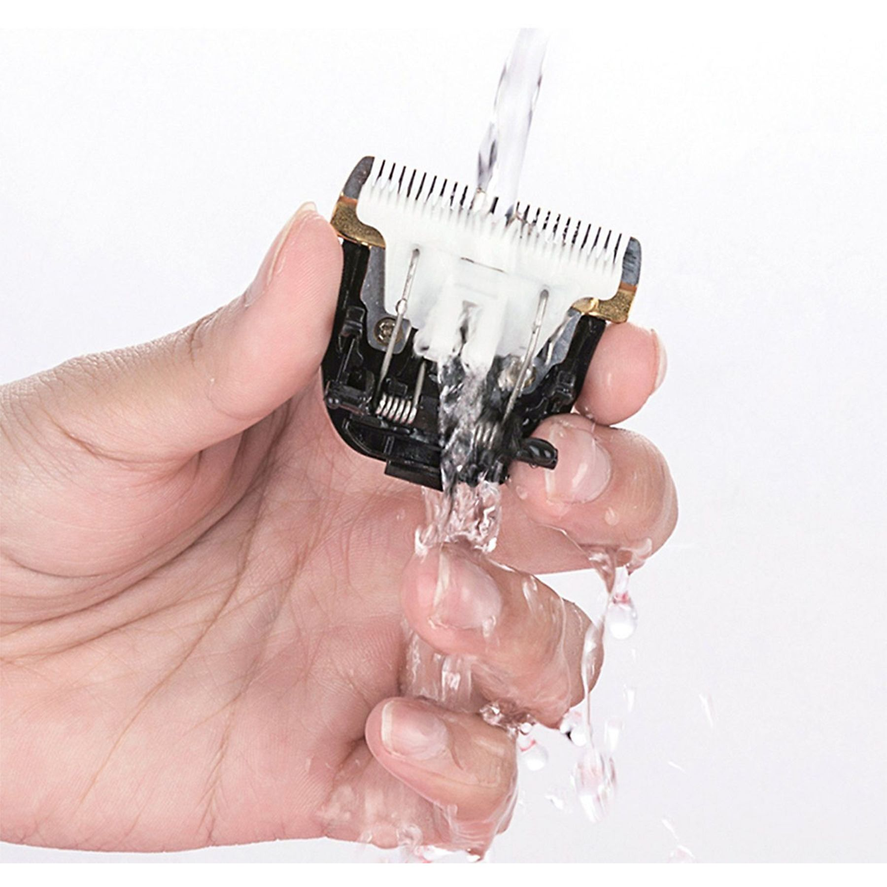 Eine Hand, die eine Haarschneidemaschinenklinge unter fließendem Wasser hält.