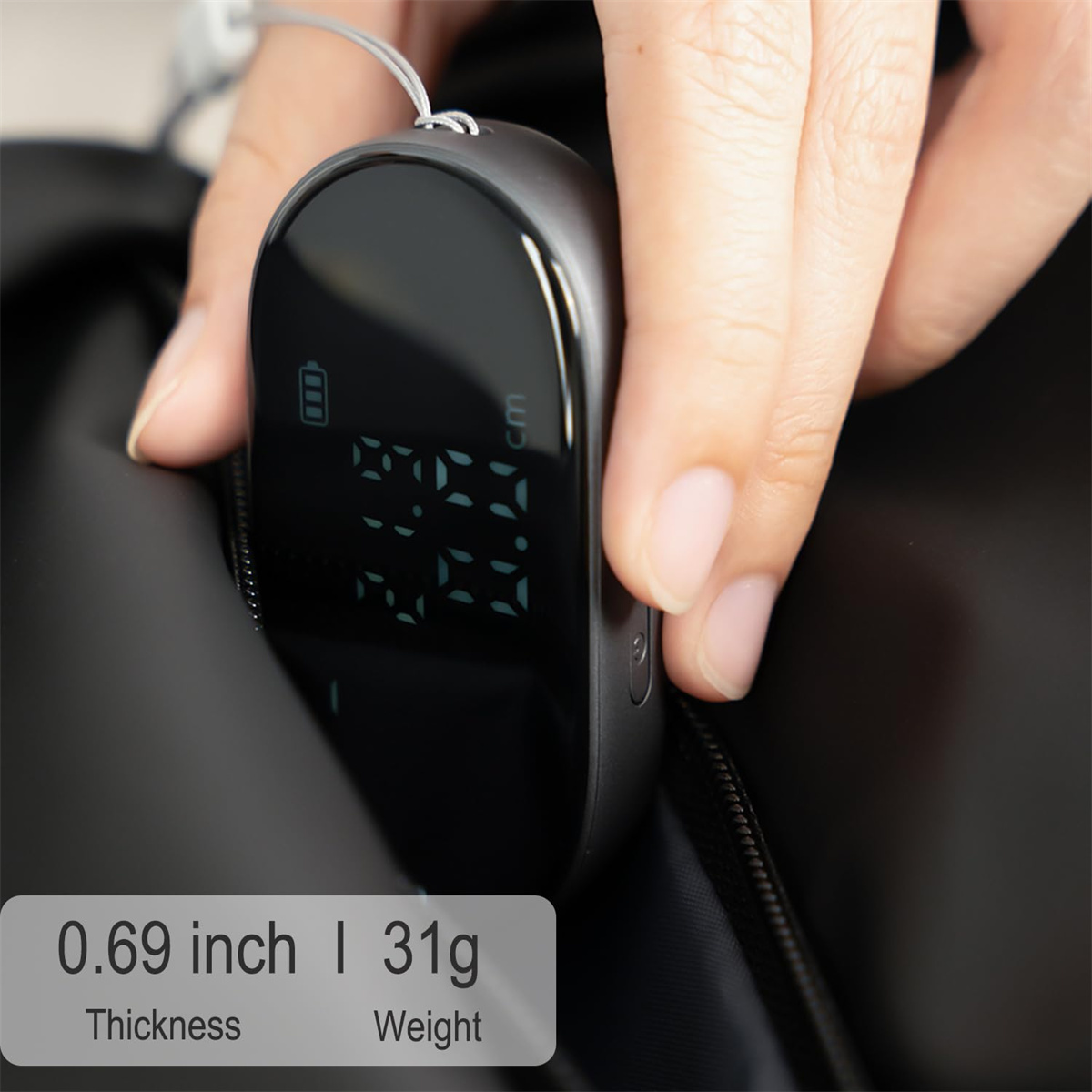 Hand hält ein schwarzes Gerät mit Zahlen. Text darunter: 0,69 Zoll Dicke, 31g Gewicht.