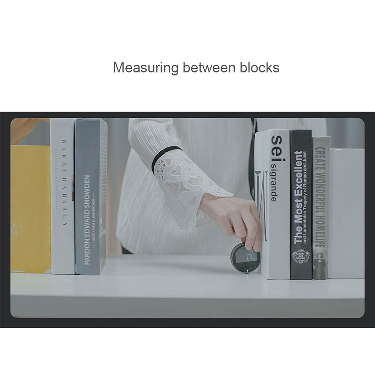 Eine Person misst zwischen zwei Büchern mit einem digitalen Messwerkzeug.