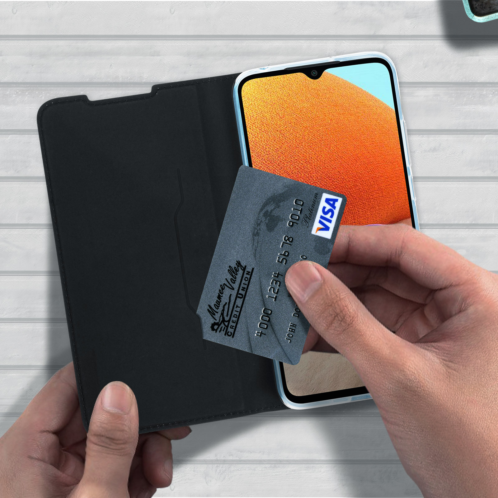 Mani che tengono un telefono in una custodia, mostrando la carta di credito all'interno e lo sfondo.