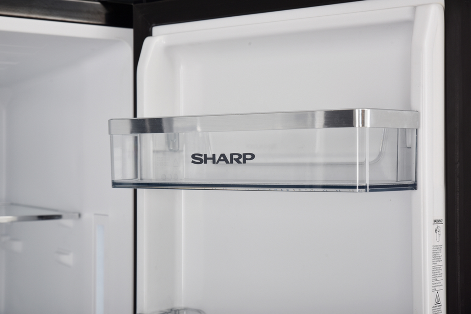 Un ripiano trasparente Sharp è all'interno di un frigorifero bianco. Sul ripiano c'è scritto SHARP.