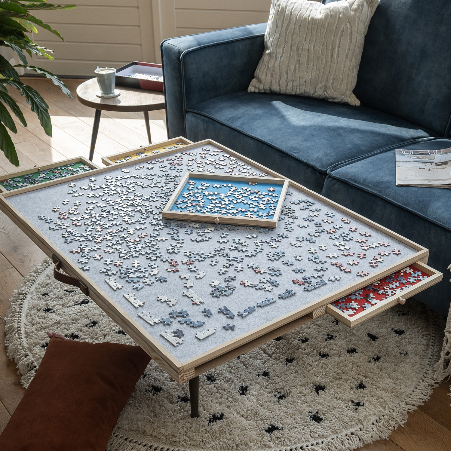 Jigsaw puzzle in progress on a table, with puzzle pieces and trays, a blue couch in background.