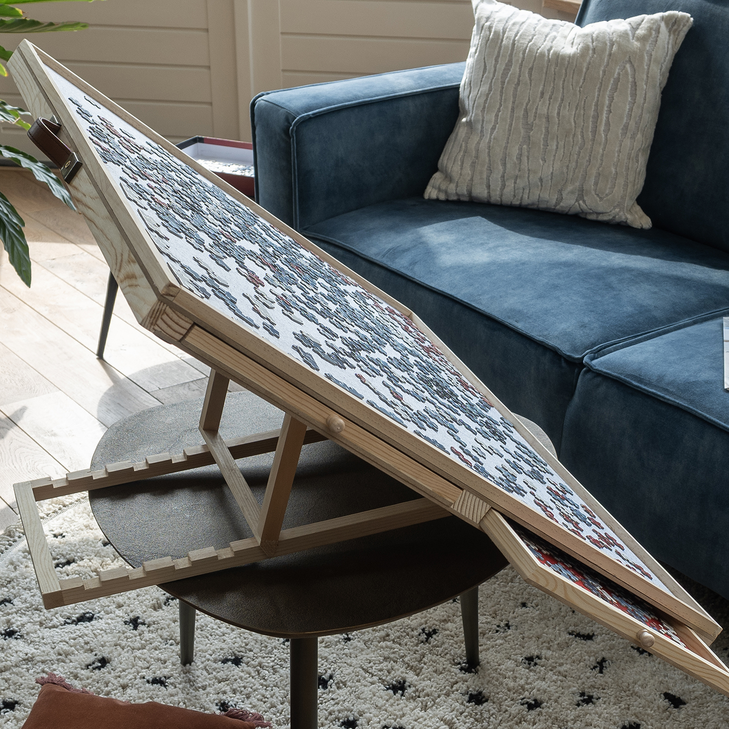 Puzzle on a table. The table is tilted. Blue sofa in the background.