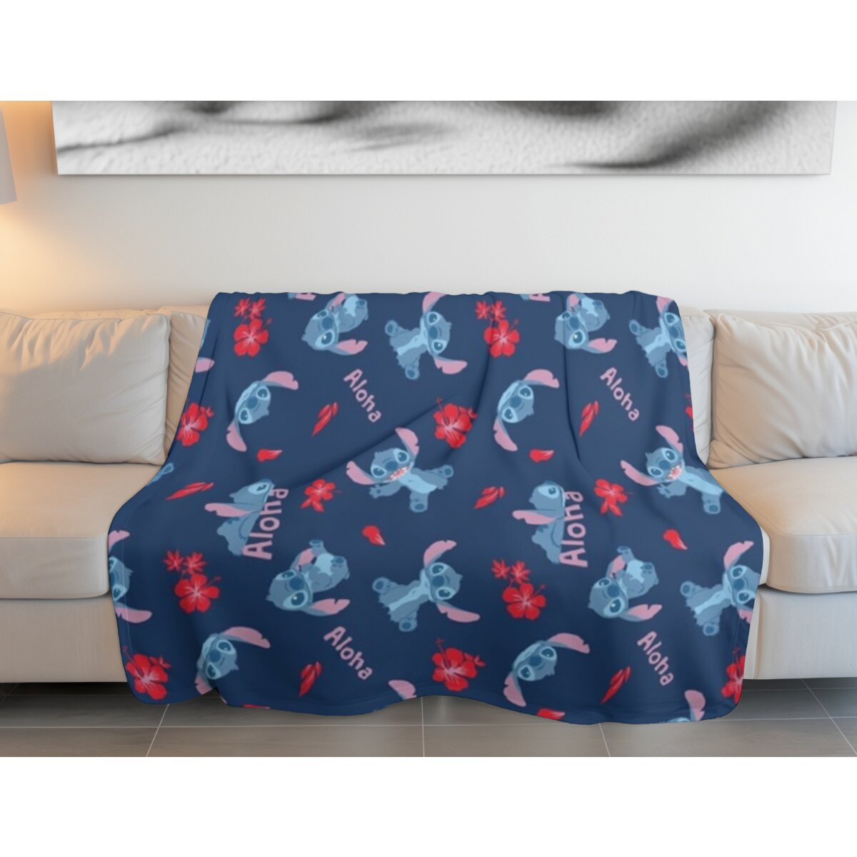 Blaue Decke mit Stitch-Figuren und Aloha-Text. Weißes Sofa im Hintergrund.