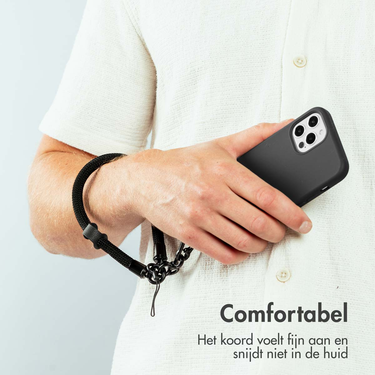 Persoon die zwarte telefoon met zwarte band vasthoudt. Wit overhemd. Tekst: Comfortabel.