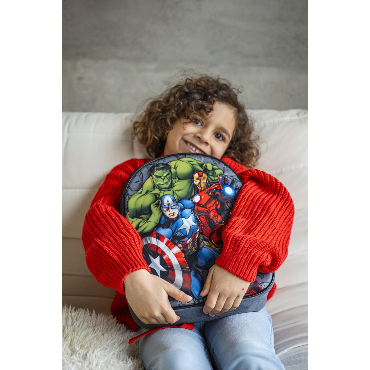 Ein Kind hält einen Avengers-Rucksack mit Hulk, Iron Man, Captain America.