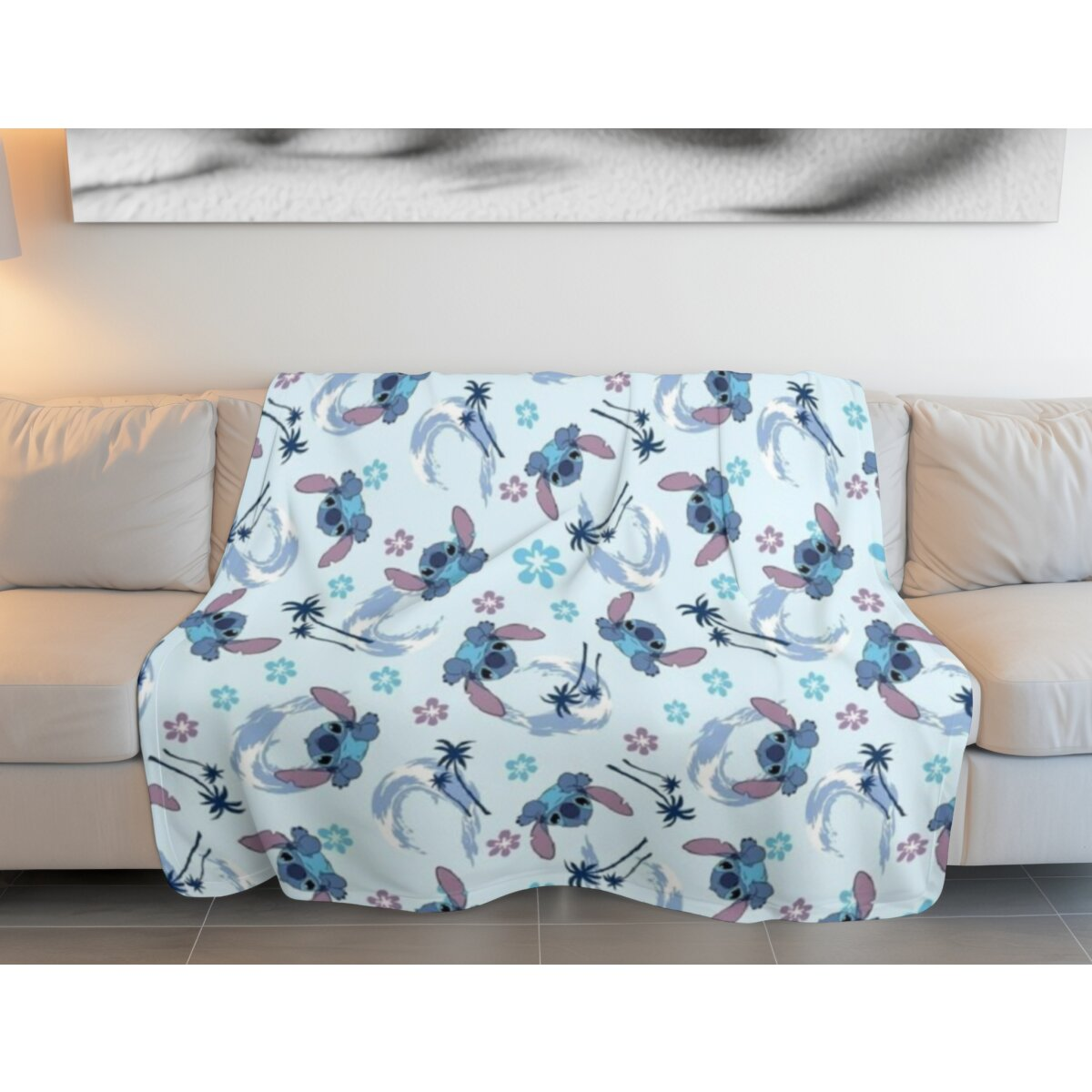 Blau-weiße Stitch-Decke auf einem Sofa. Die Decke hat ein Muster aus Stitch-Figuren und Blumen.