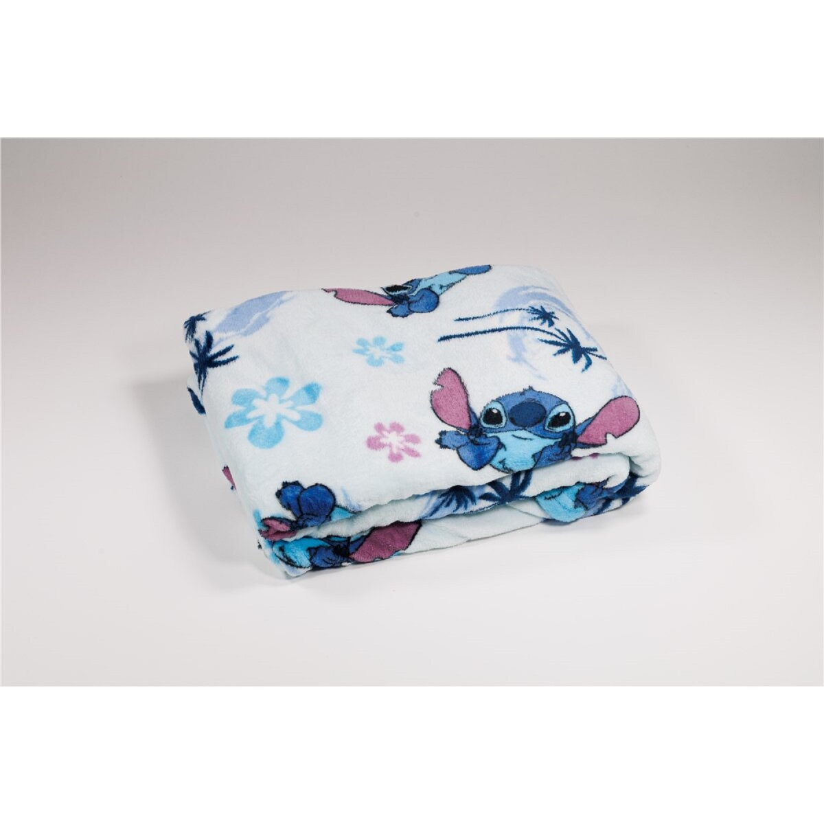 Gefaltete Decke mit einem Cartoon-Stitch-Design. Sie ist weiß mit blauen, rosa und lila Akzenten.