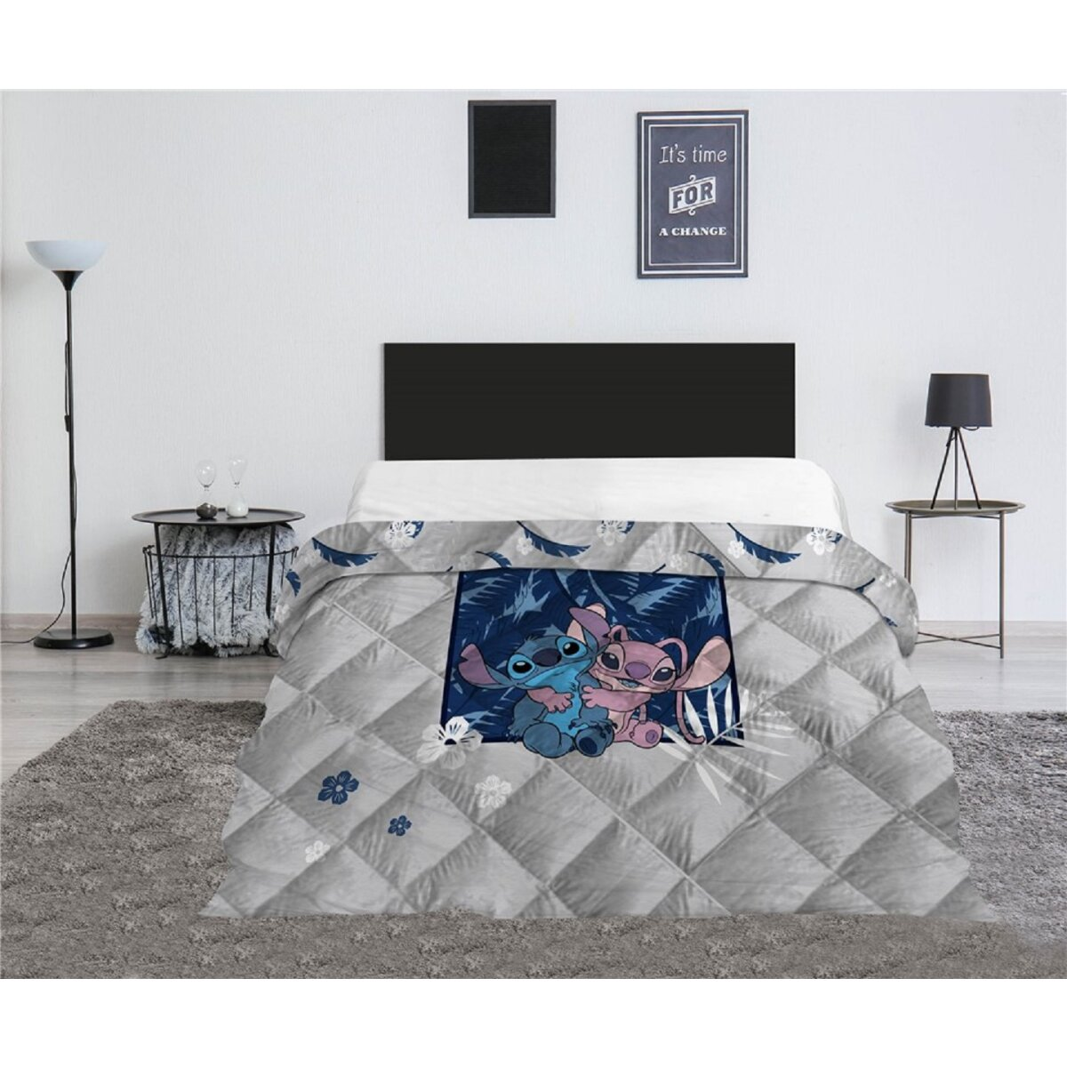 Ein Bett mit einer grauen Steppdecke mit Stitch- und Angel-Figuren.