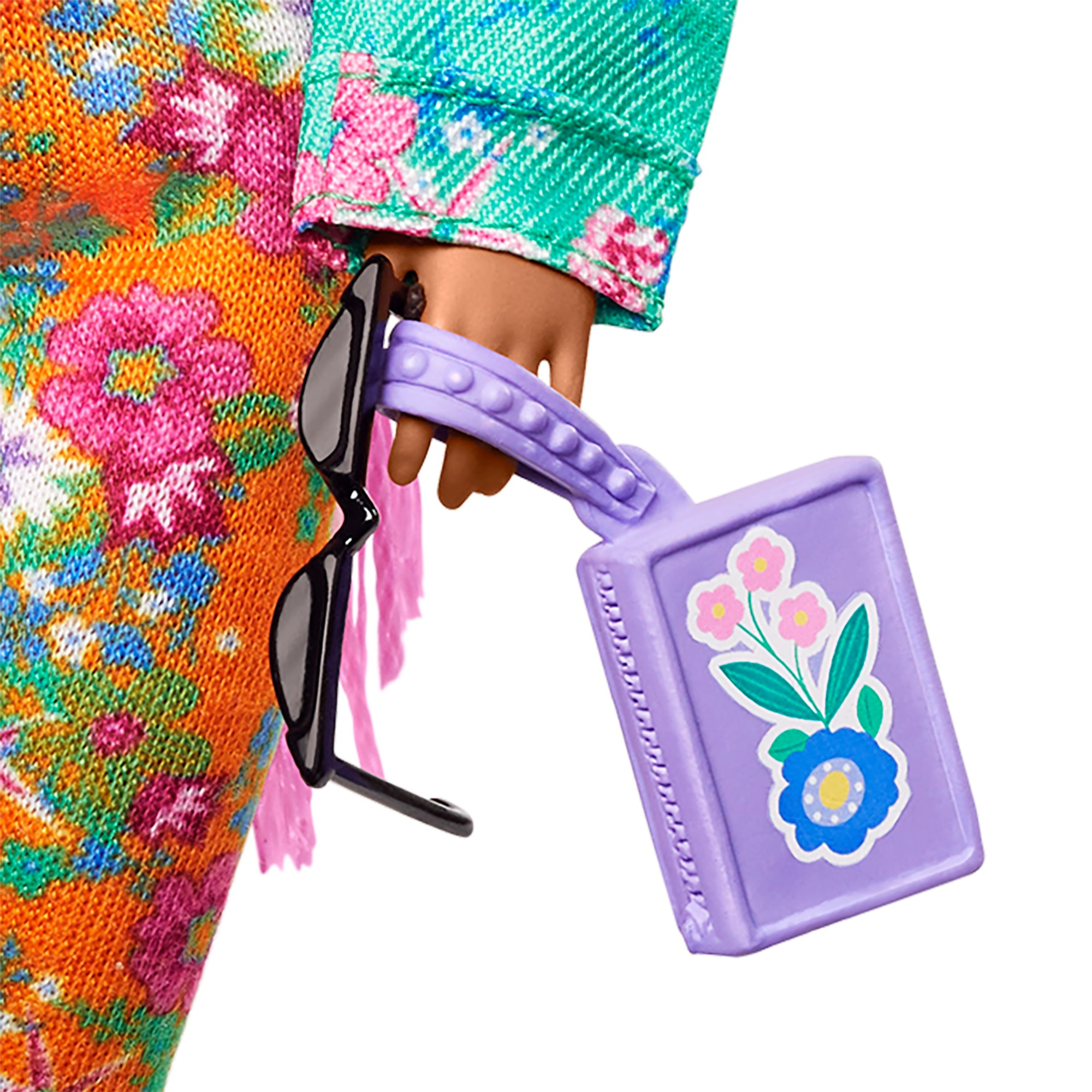 Nahaufnahme der Hand einer Barbie-Puppe, die eine Sonnenbrille und eine lila Handtasche hält.