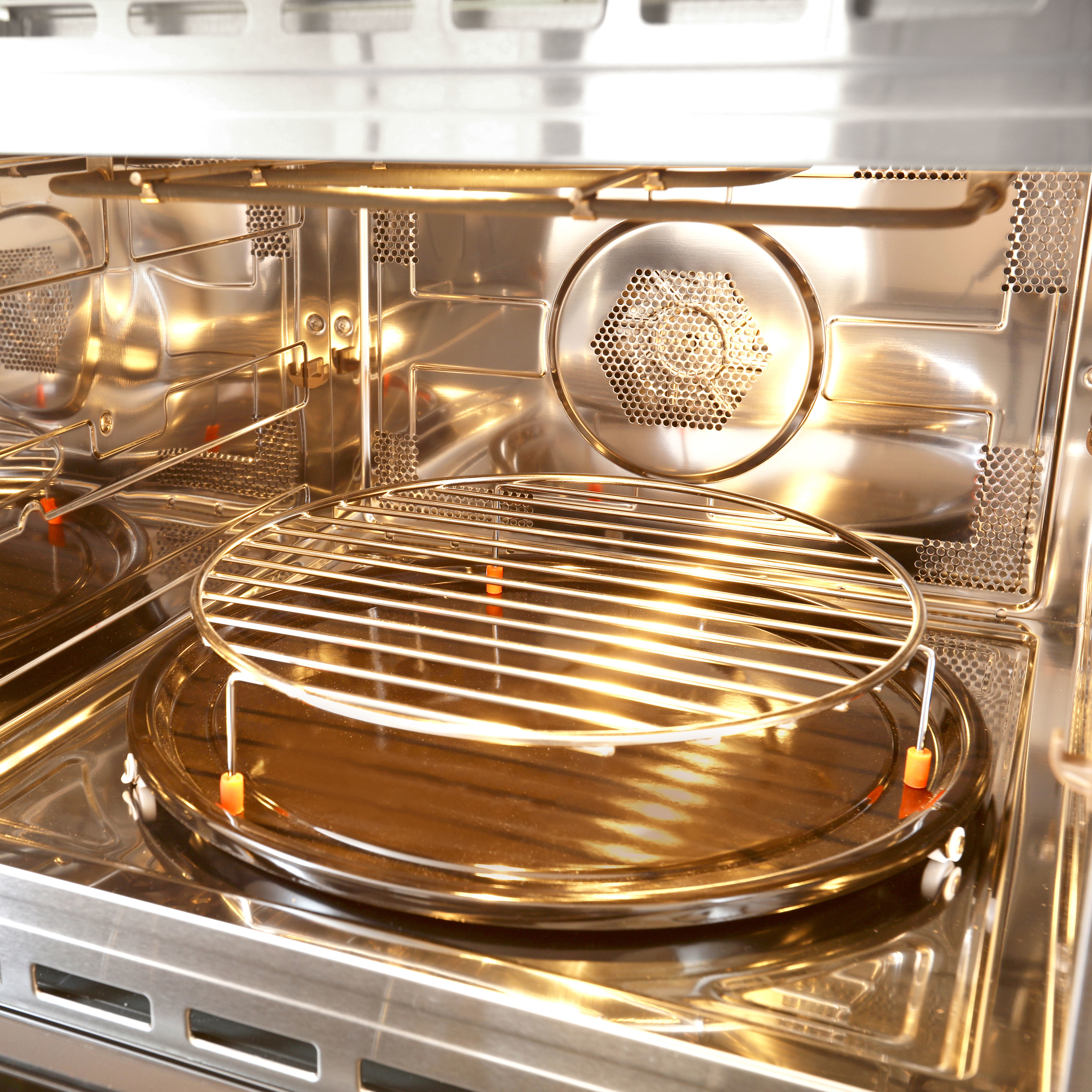 Binnenkant van de open magnetron, met een grill en ventilator zichtbaar.