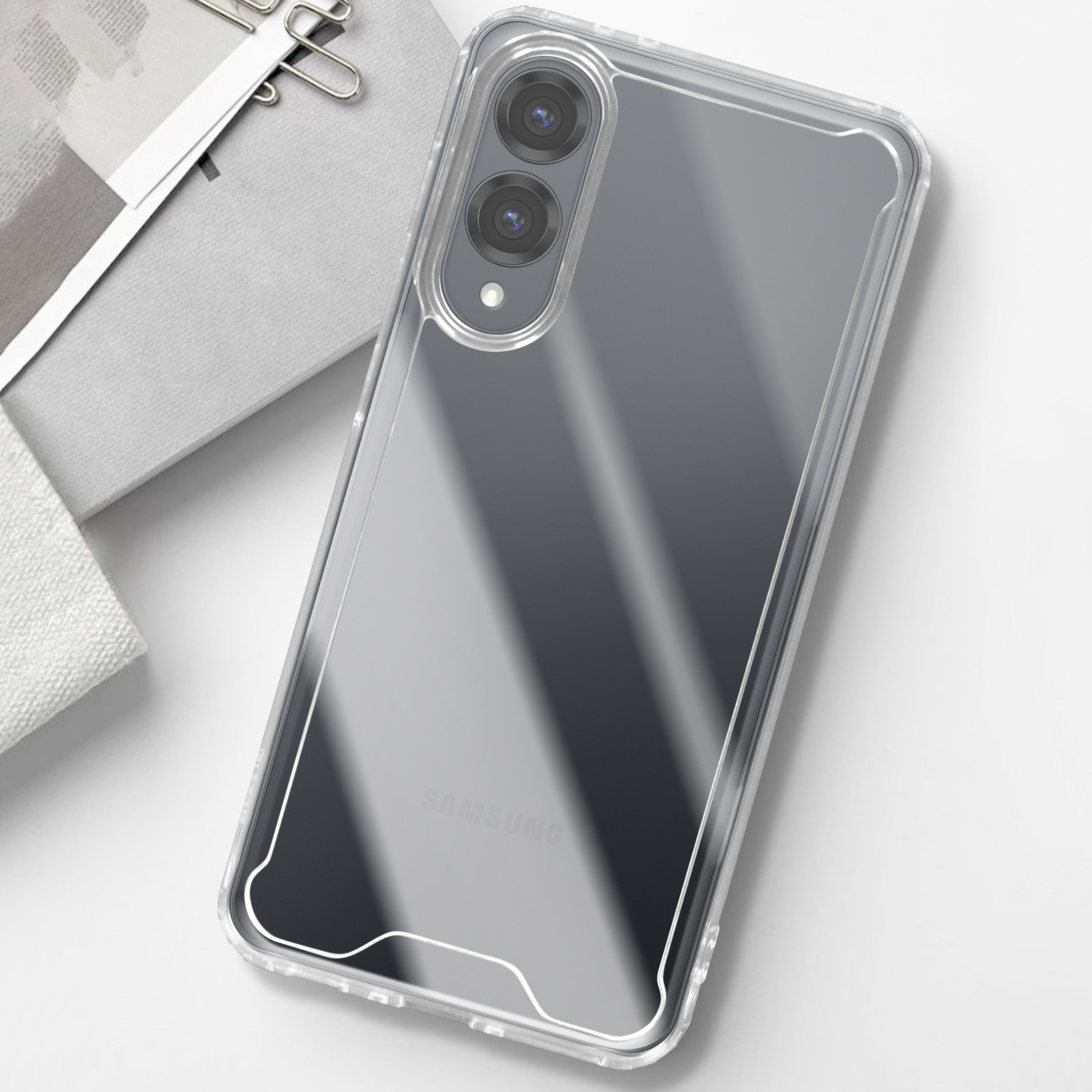 Un telefono in una custodia trasparente su una superficie bianca. La parola "SAMSUNG" è visibile.