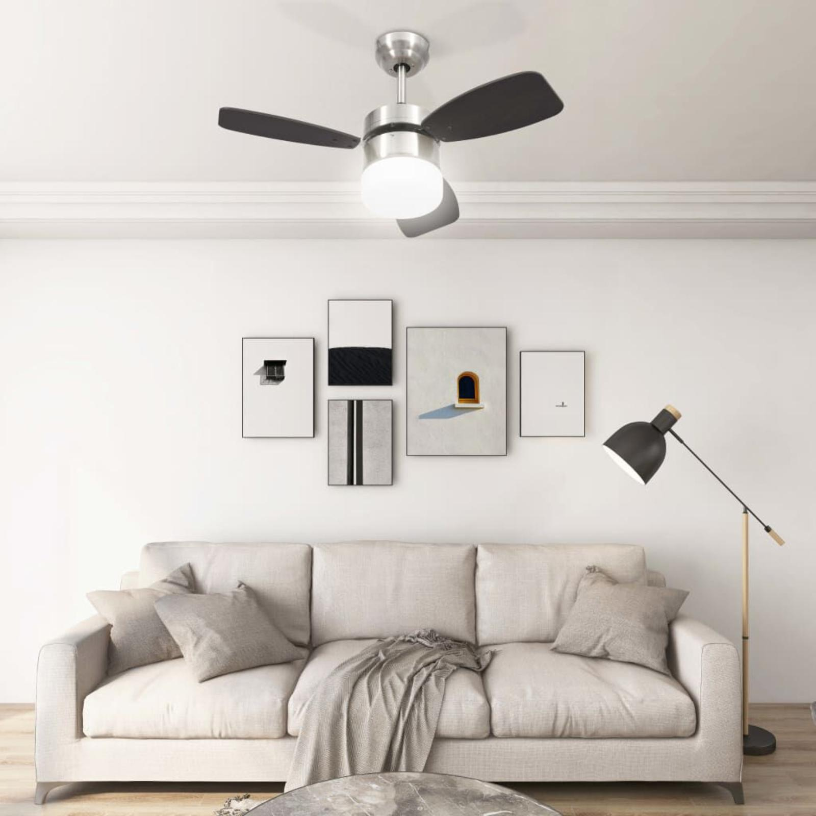 Deckenventilator mit drei dunklen Flügeln und einem Licht. In einem Raum mit Sofa und Kunst.