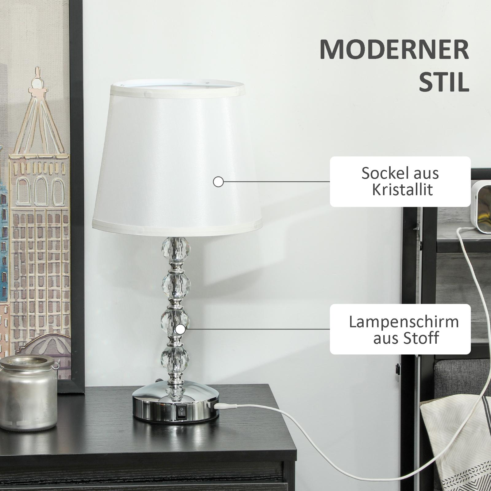 Tischlampe mit weißem Schirm, Kristallfuß. Text und Gegenstände auf dem Tisch.