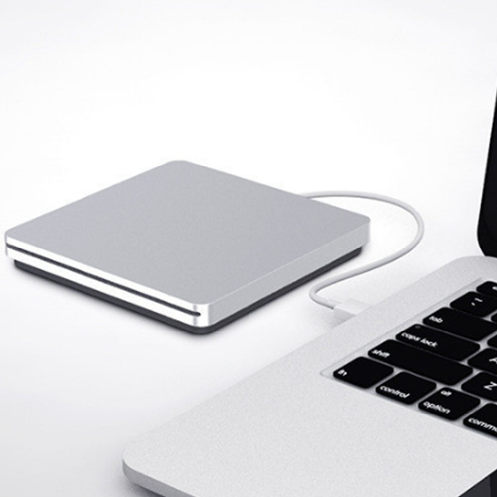 Silbernes externes CD/DVD-Laufwerk, an einen Laptop angeschlossen. Der Laptop ist auf einer weißen Oberfläche geöffnet.