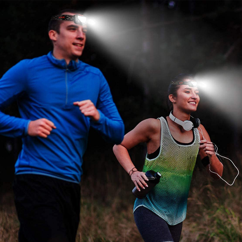Zwei Personen laufen mit Stirnlampen im dunklen Wald.