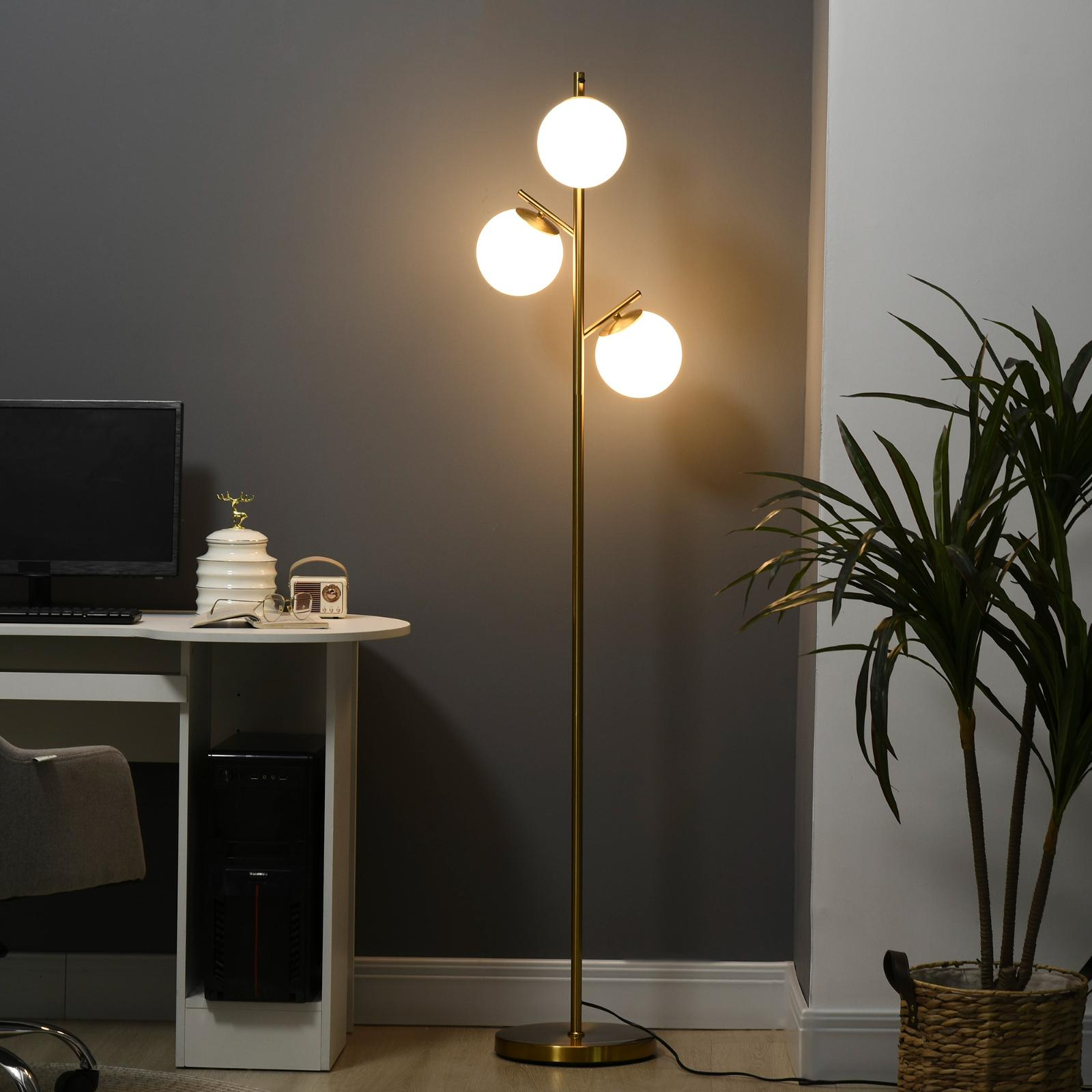 Eine Stehlampe mit drei Glühbirnen und ein Schreibtisch mit Computer.