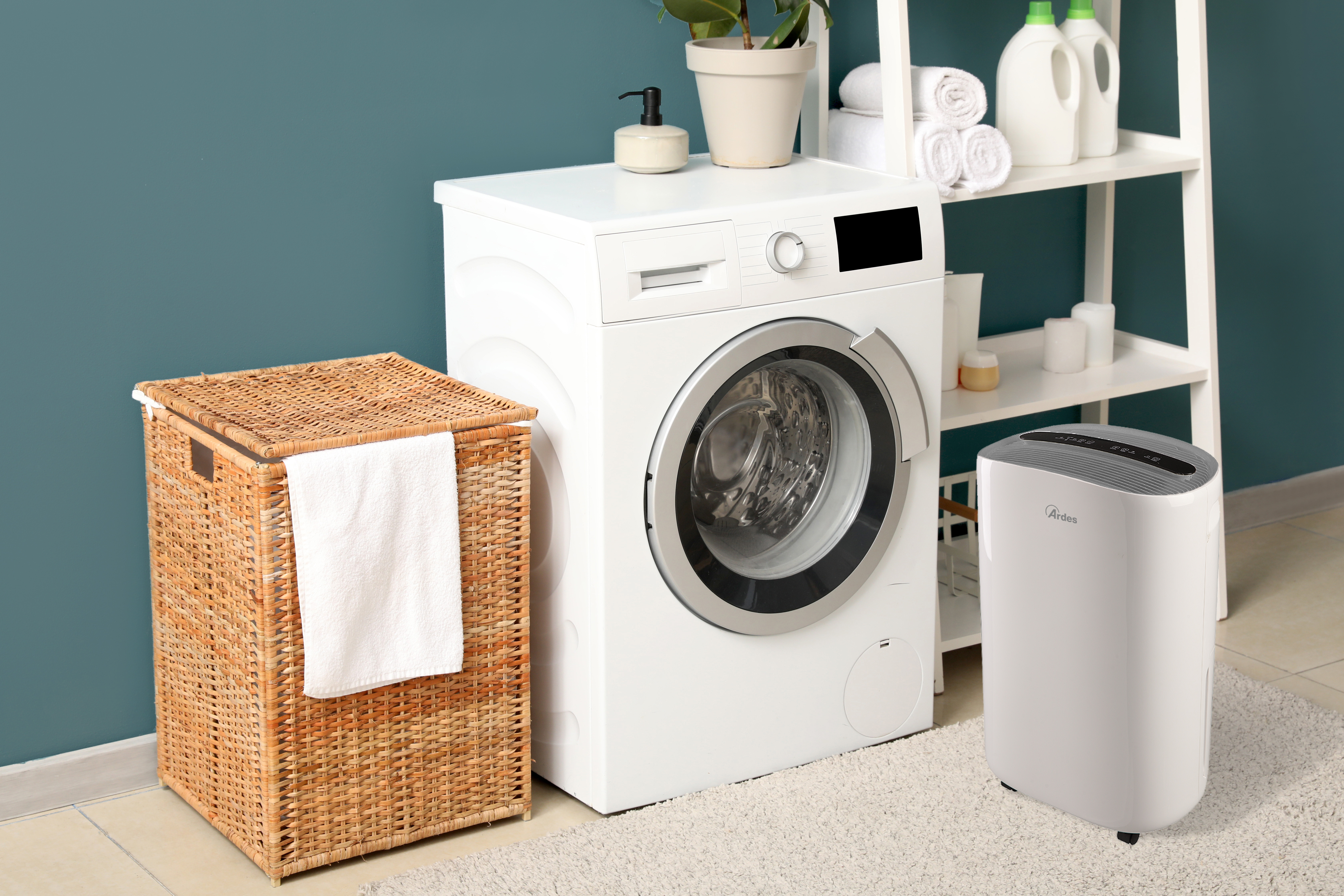 Scena w pralni z pralką, wiklinowym koszem i białym oczyszczaczem powietrza.