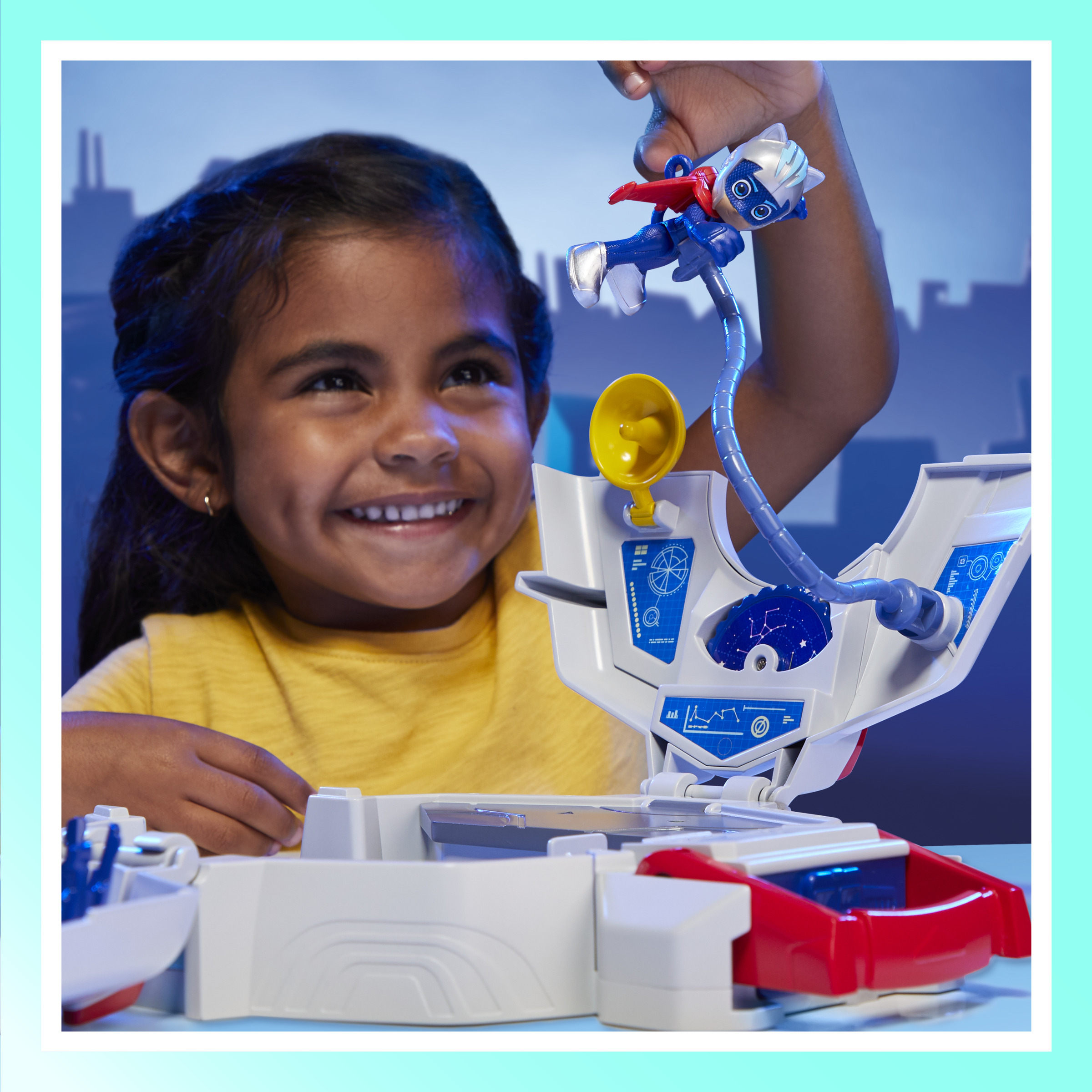 Een meisje lacht naar een PJ Masks-speelset. Catboy-figuur is bevestigd aan een speelset. Wit en blauw thema speelset.