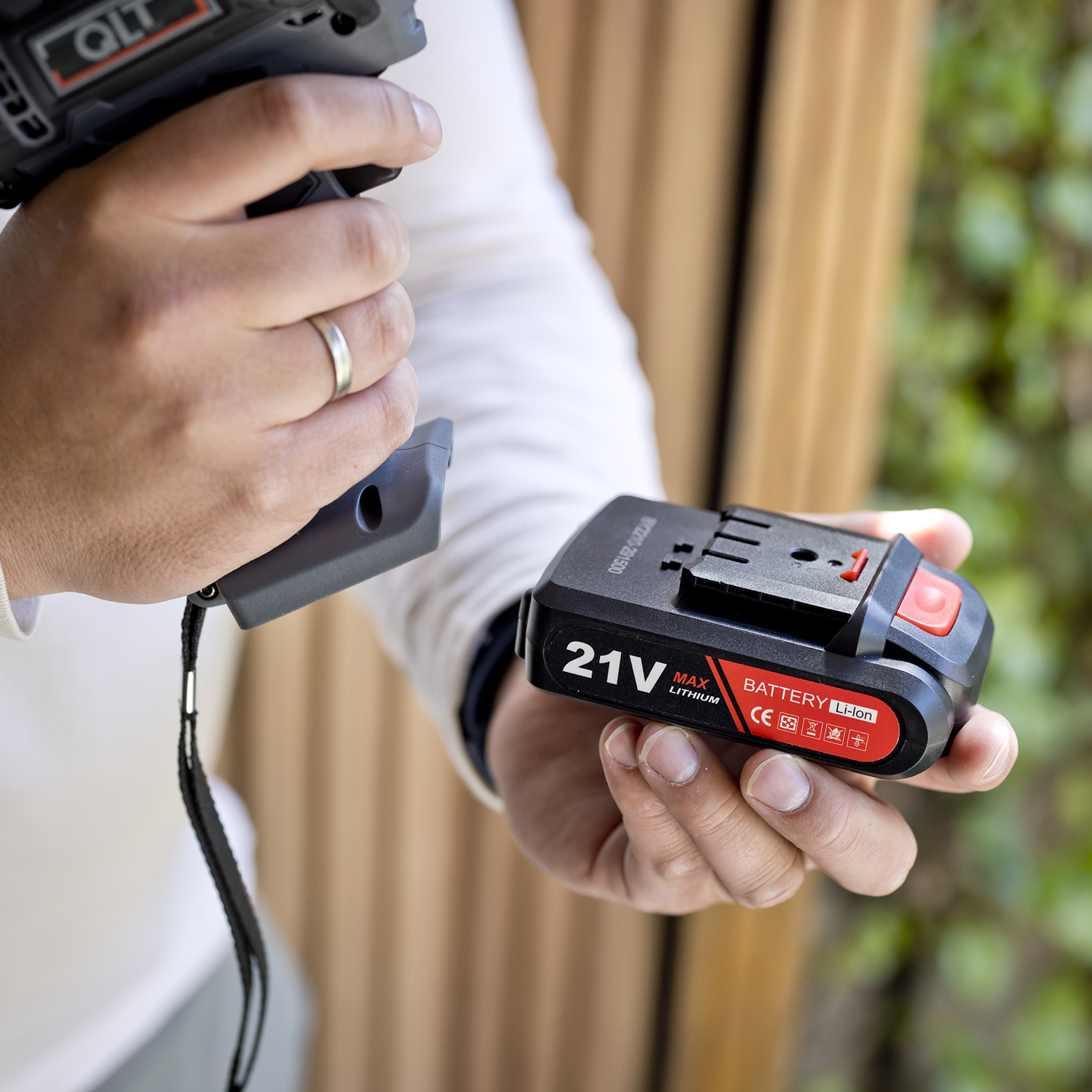 Hand die een boorbatterij vasthoudt. De batterij is zwart, rood en heeft een rating van 21V.