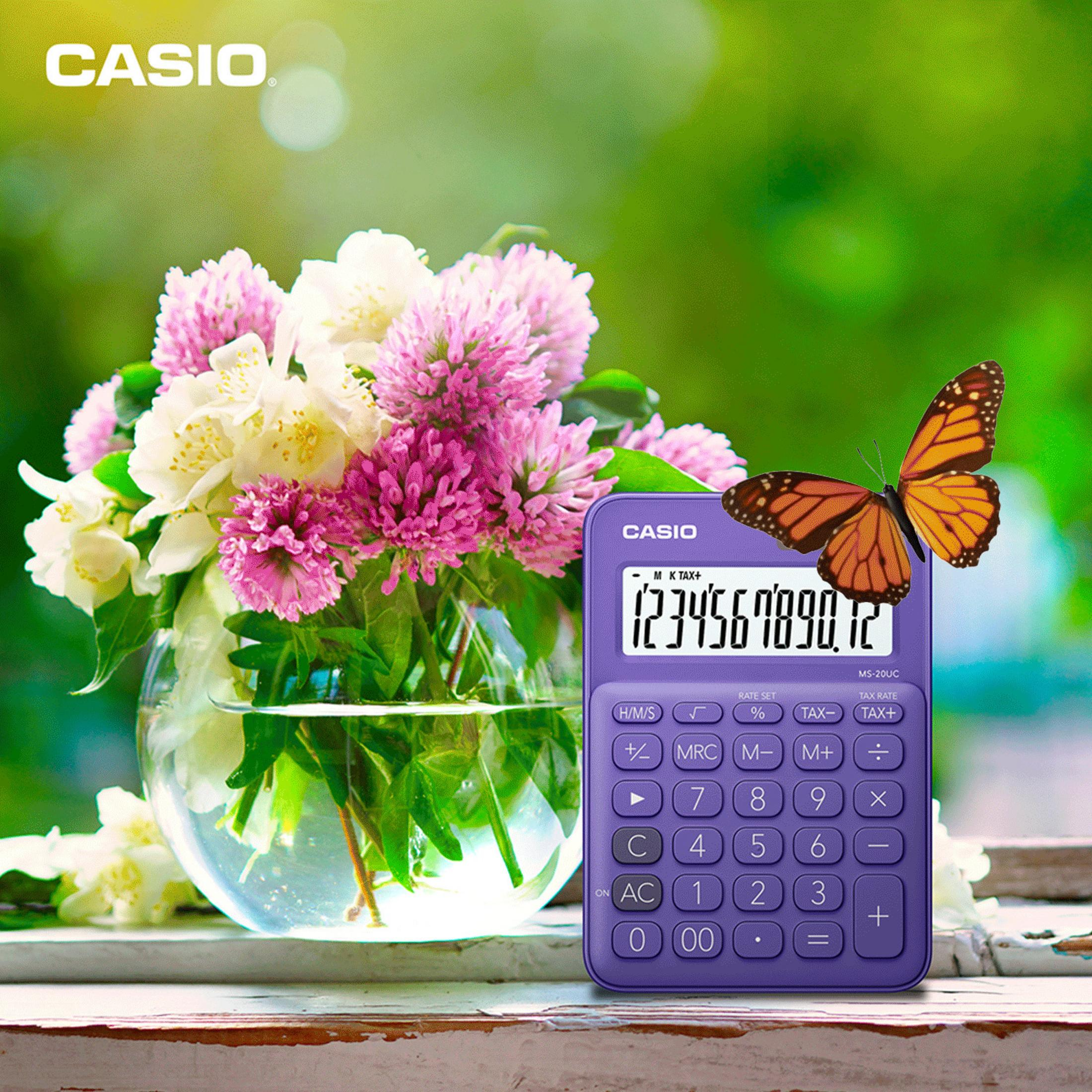 Lila Taschenrechner und eine Blumenvase mit Schmetterling. Der Hintergrund ist unscharf.