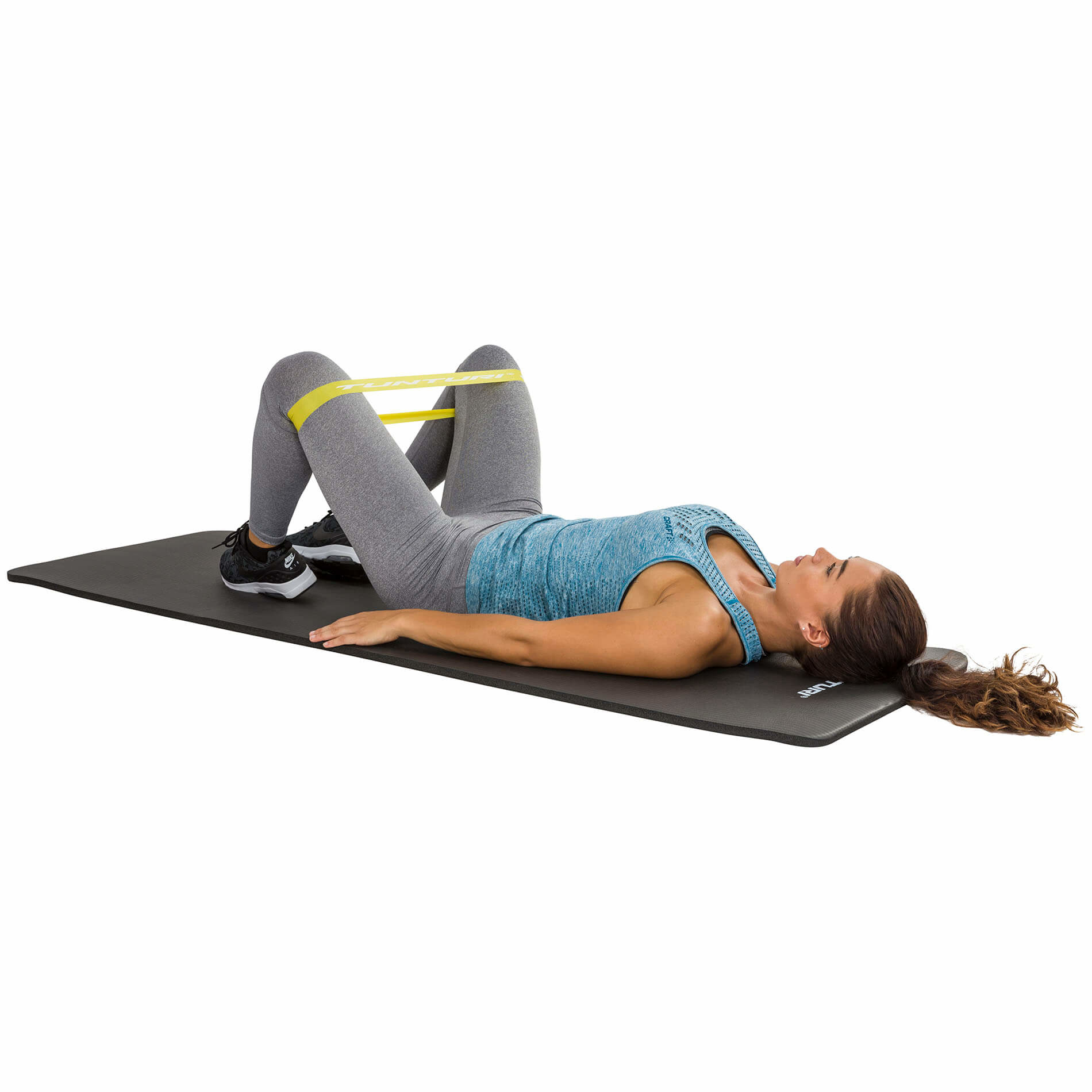 Kobieta ćwicząca z żółtą taśmą oporową na macie, leżąca na plecach.