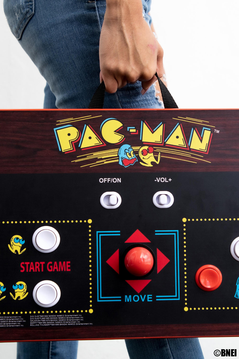 Una persona che tiene in mano un controller arcade di Pac-Man con il logo del gioco e i pulsanti visibili.