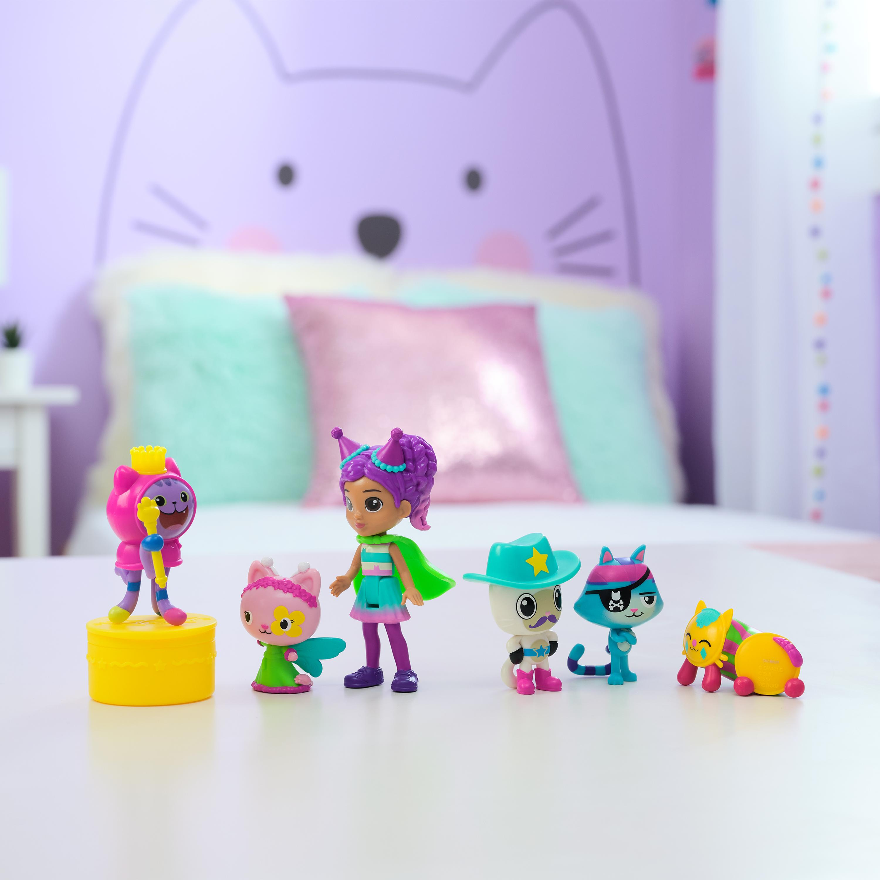 Figurki z motywem kota na stole, z figurką dziewczynki. Tło to pokój ze sztuką kotów.