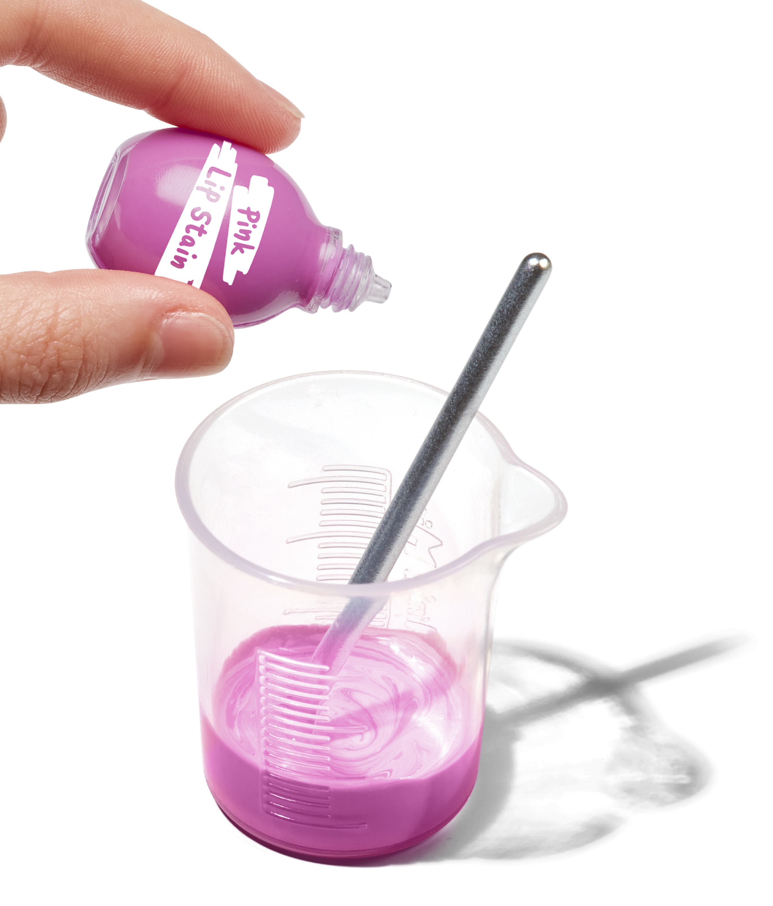 Różowa farba do ust w trakcie mieszania. Butelka jest wlewana do zlewki, z prętem mieszającym.