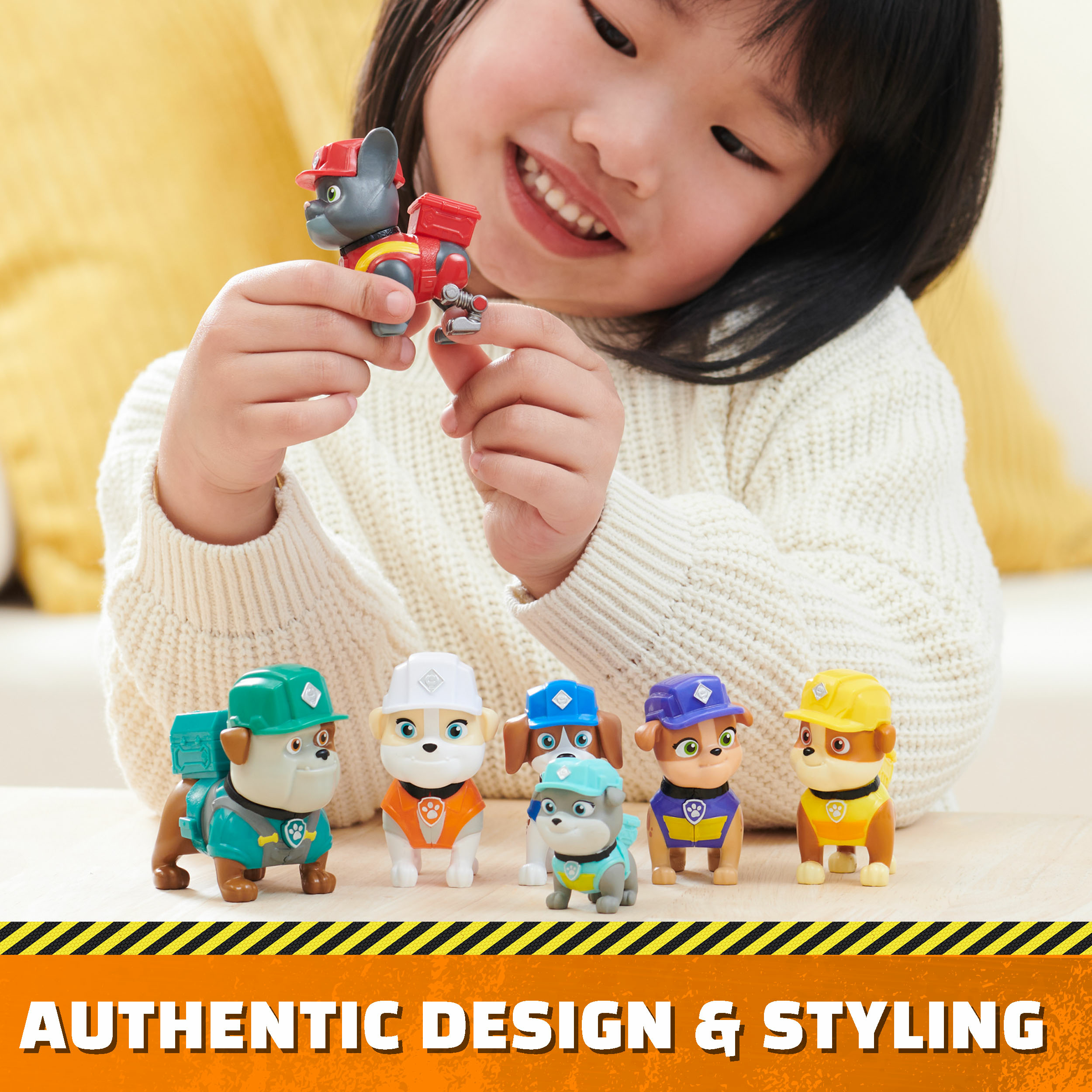 Młoda dziewczyna bawi się figurkami zabawek z Psiego Patrolu. Inne zabawki psy są na stole.