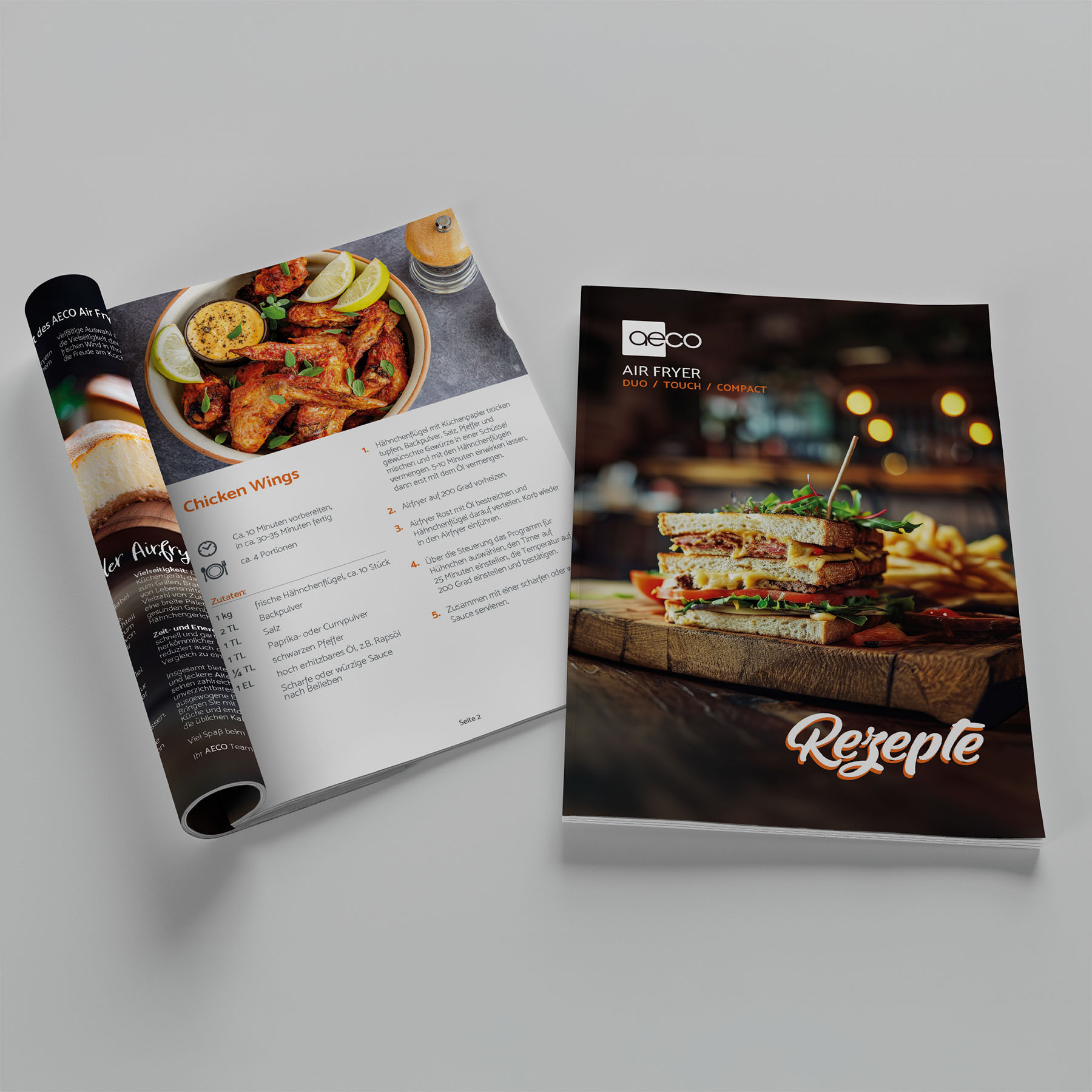 Offenes Magazin mit Hähnchenflügel-Rezept und geschlossenes Magazin mit Sandwich-Rezept. Weißer Hintergrund.
