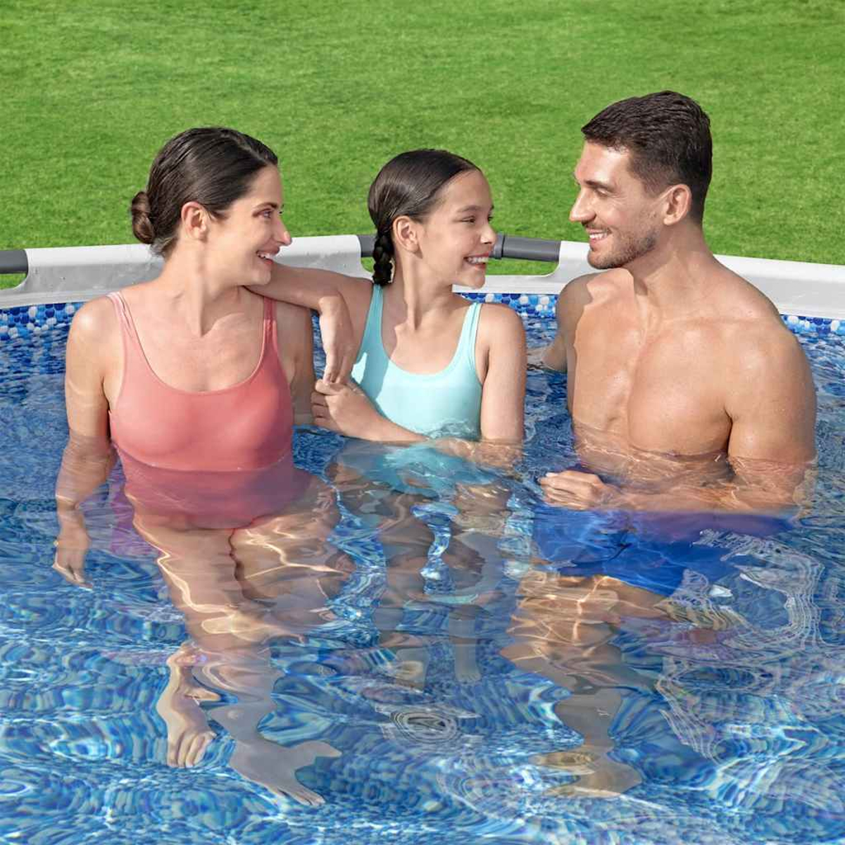 Drei Personen in einem Pool: eine Frau, ein Mädchen und ein Mann. Das Wasser reflektiert ihre Körper. Der Hintergrund ist grün.