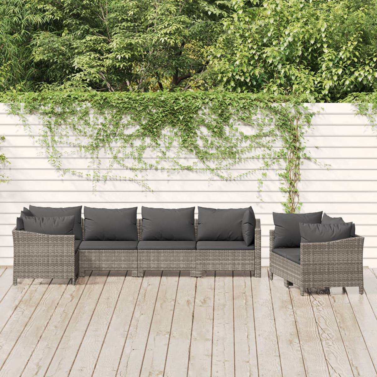 Gartenmöbel-Set aus grauem Korbgeflecht. Enthält ein Sofa, einen Stuhl und Kissen. Holzterrasse.