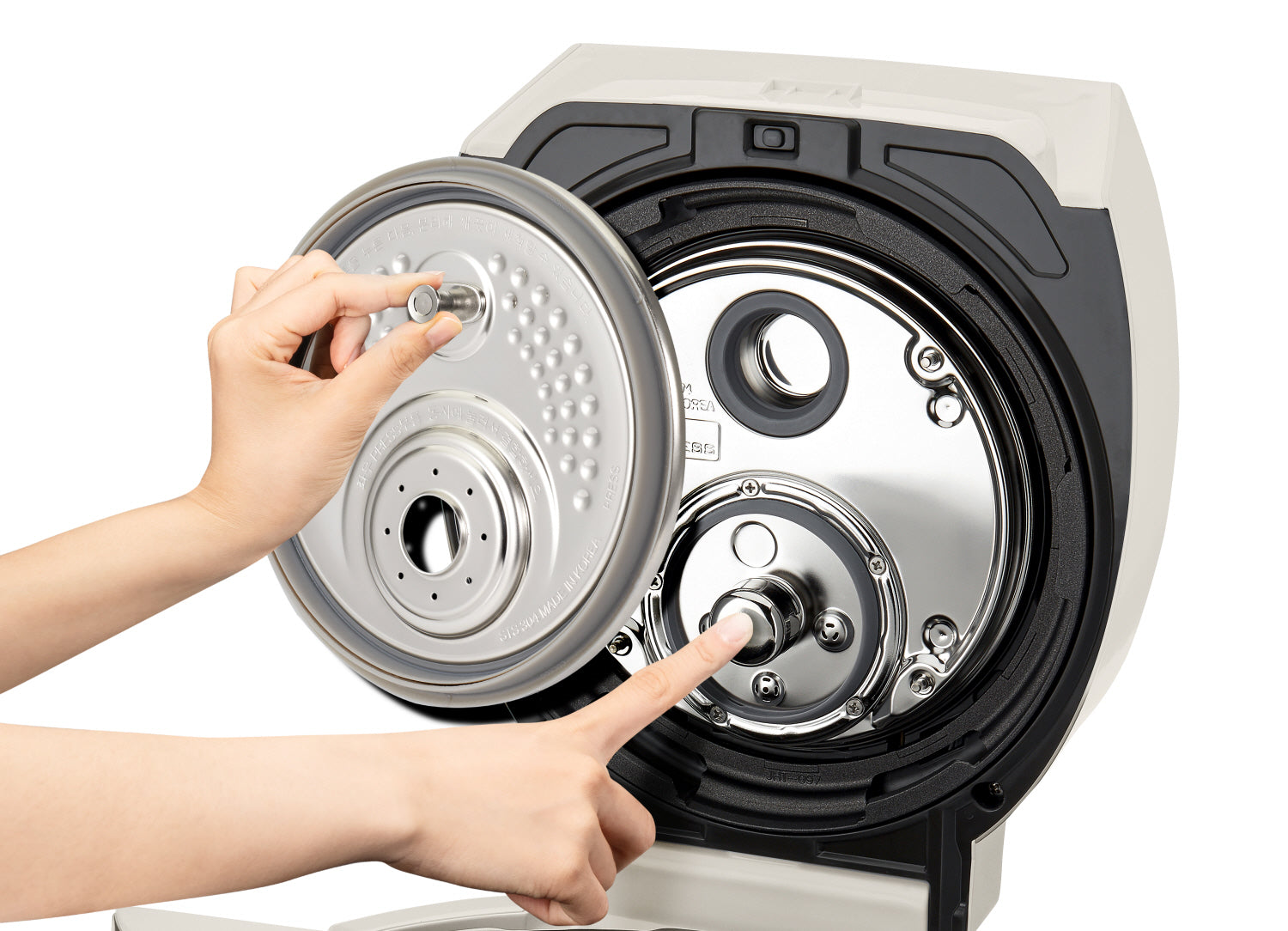 Hände, die einen Deckel von einem Reiskocher abnehmen, zeigen die inneren Komponenten.