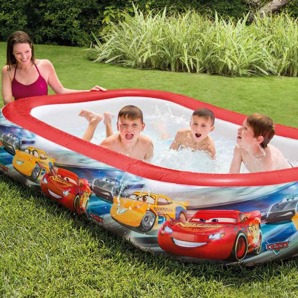 Kinder in einem Pool mit Auto-Grafiken, beobachtet von einer Frau.