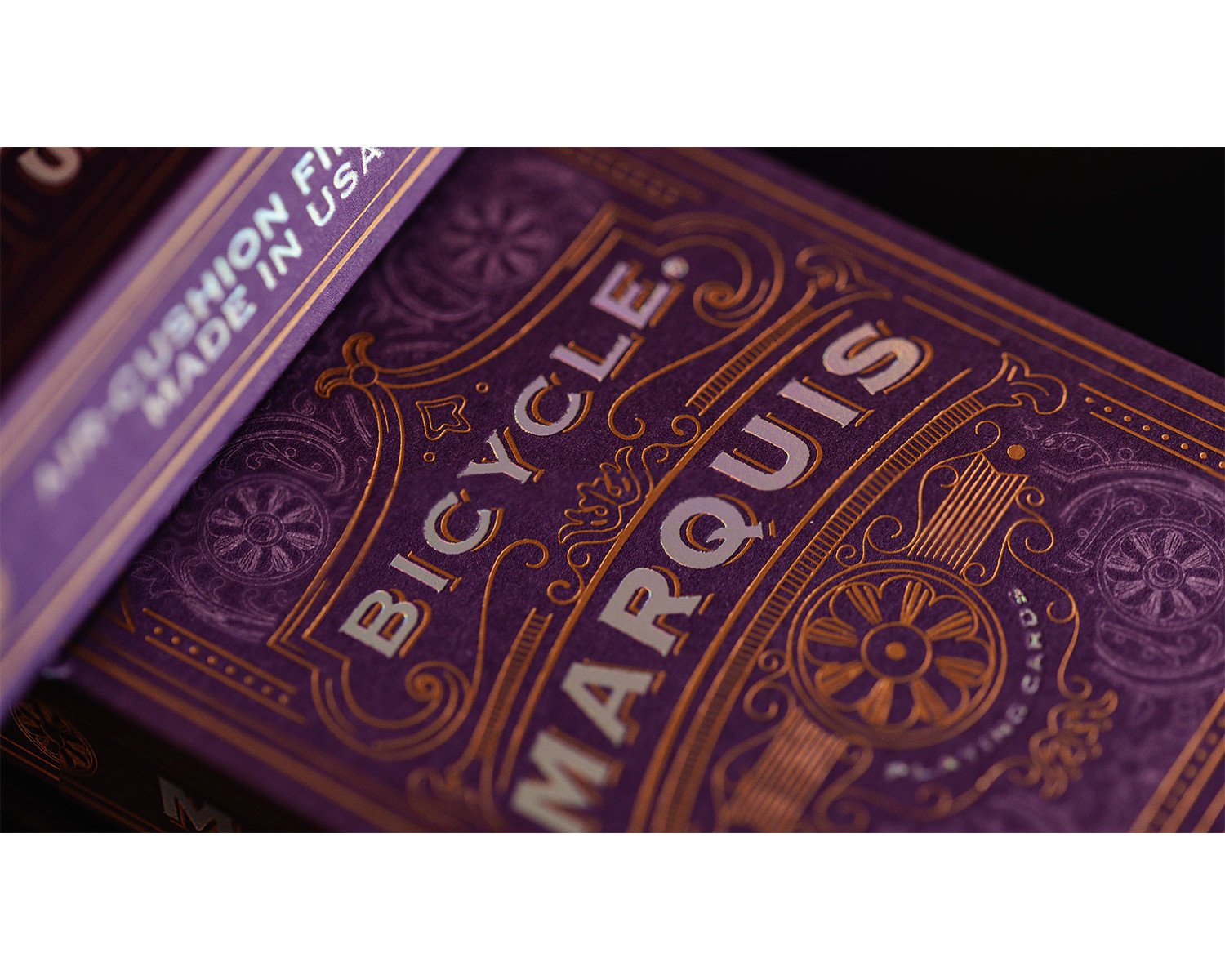 Ein Deck Bicycle Marquis Spielkarten liegt auf einer Oberfläche. Die Karten sind lila mit goldfarbenen Buchstaben und Designs.