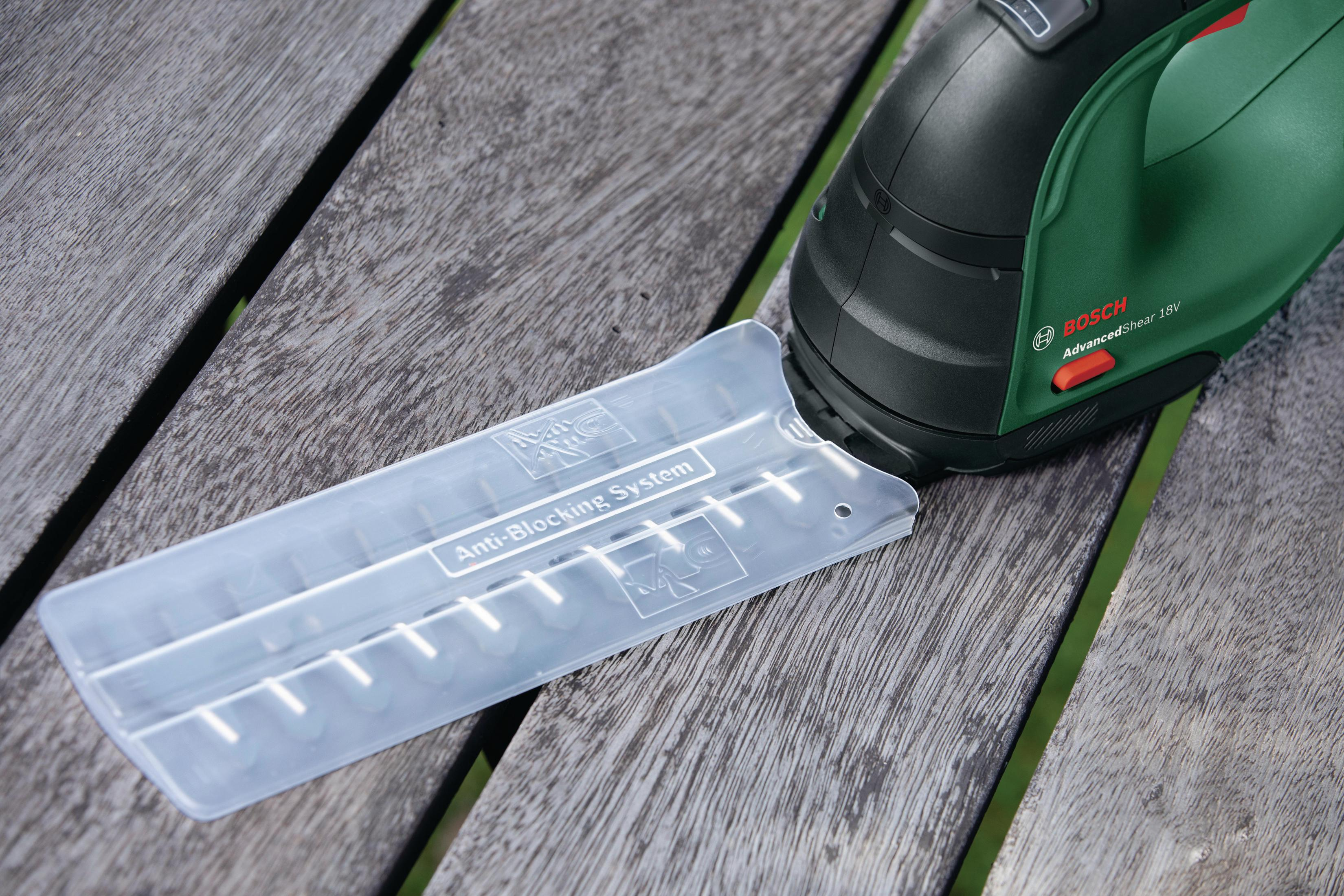 Nożyce do żywopłotu Bosch z osłoną systemu antyblokującego na drewnianej powierzchni.