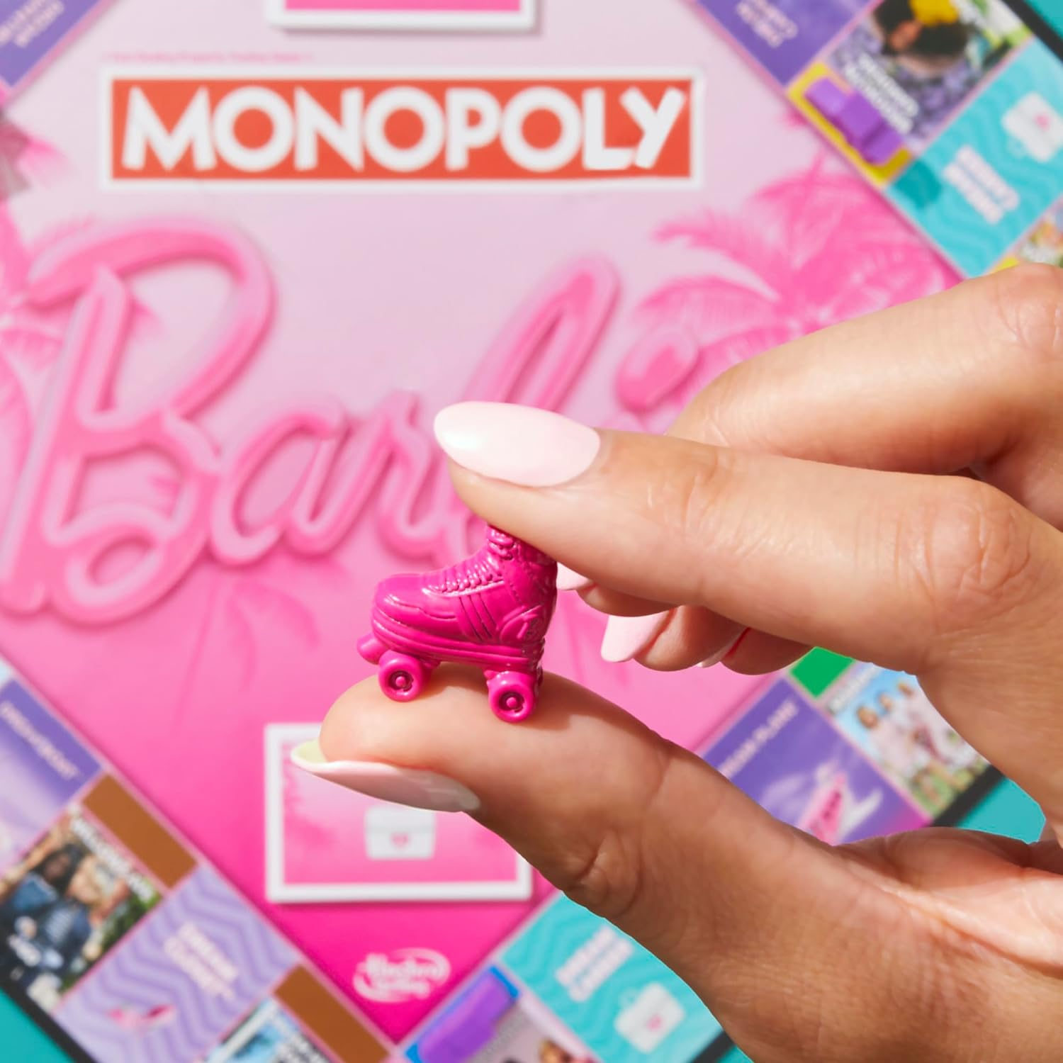 Hand hält Monopoly-Figur Rollschuh auf pinkem Barbie-Spielbrett.
