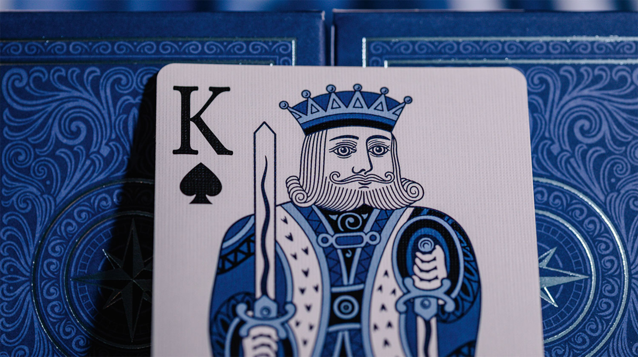 König Pik Karte mit blau detailliertem Design neben einer blauen Kartenbox.