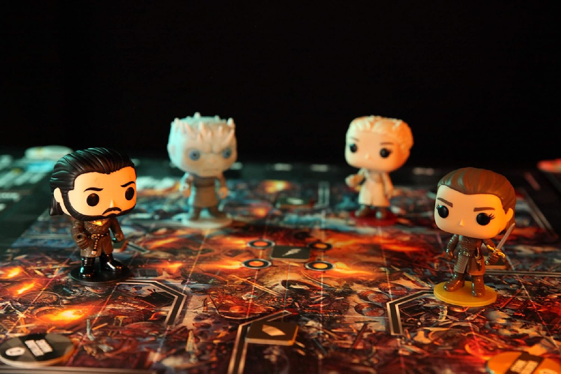 Vier Game of Thrones Funko Pop Figuren auf einem Brettspiel. Der Hintergrund ist schwarz.