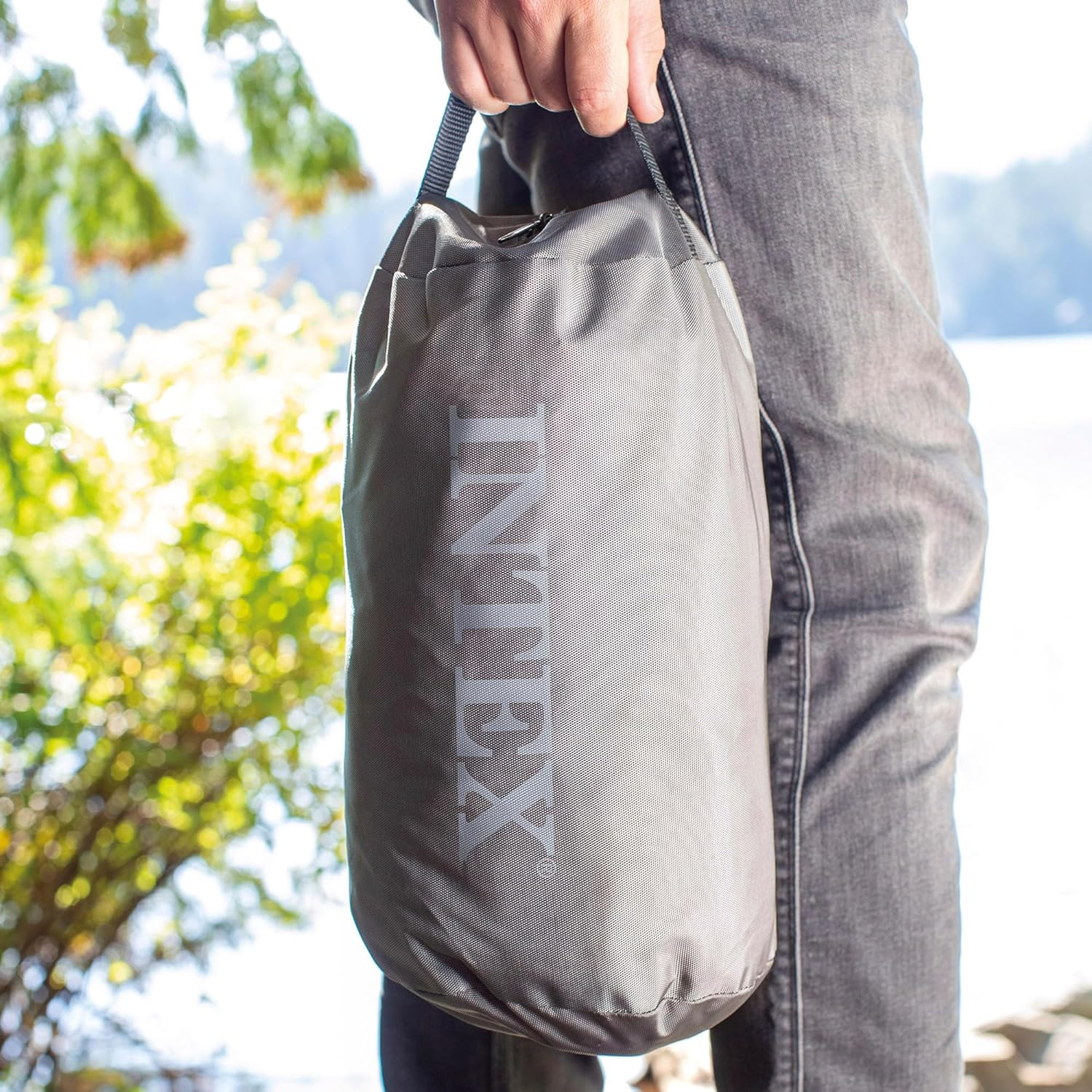 Een persoon die een grijze Intex-tas vasthoudt met een wit Intex-logo erop.